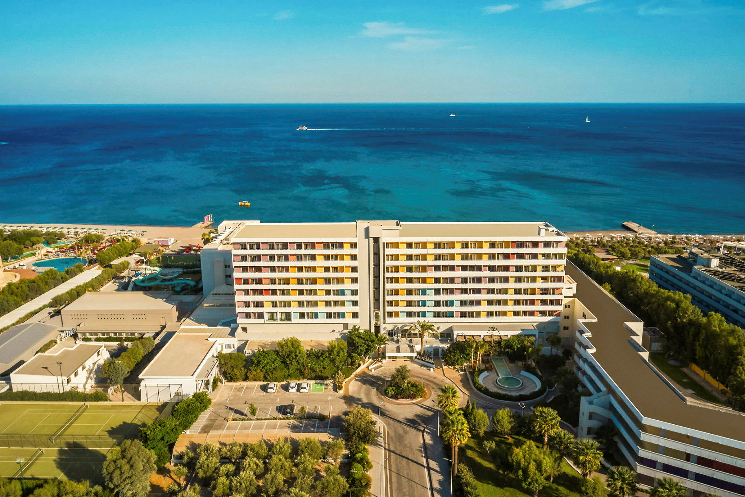 Flygvy av ett hotell på en kust med hav och strand i bakgrunden. (AI-genererad text)