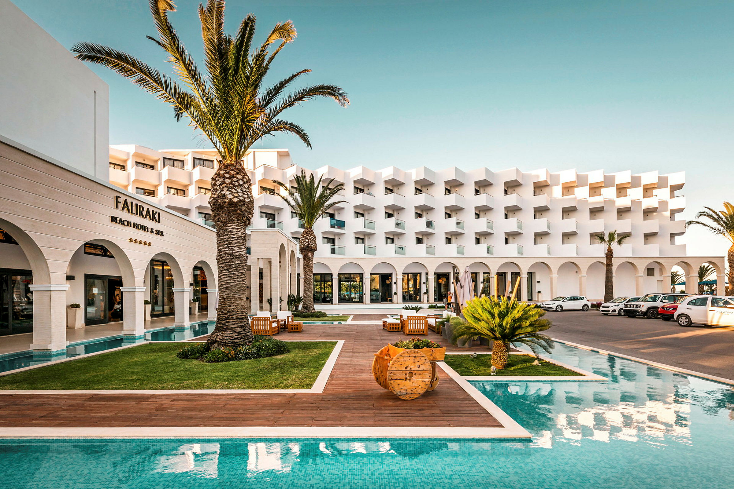 Hotellfasad med pool och palmer. (AI-genererad text)