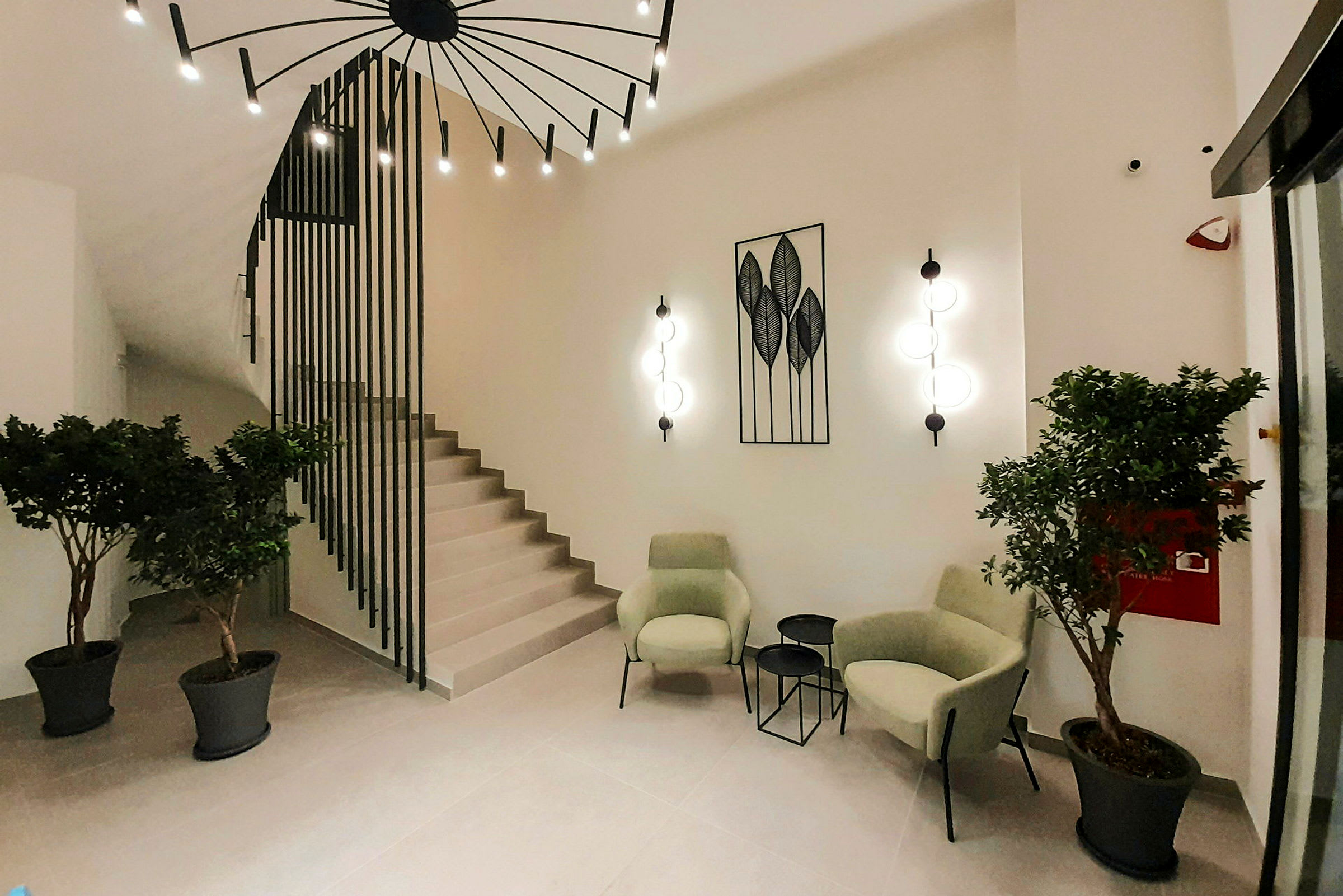 Modern lounge med gröna fåtöljer, små bord och växtlig dekoration. (AI-genererad text)