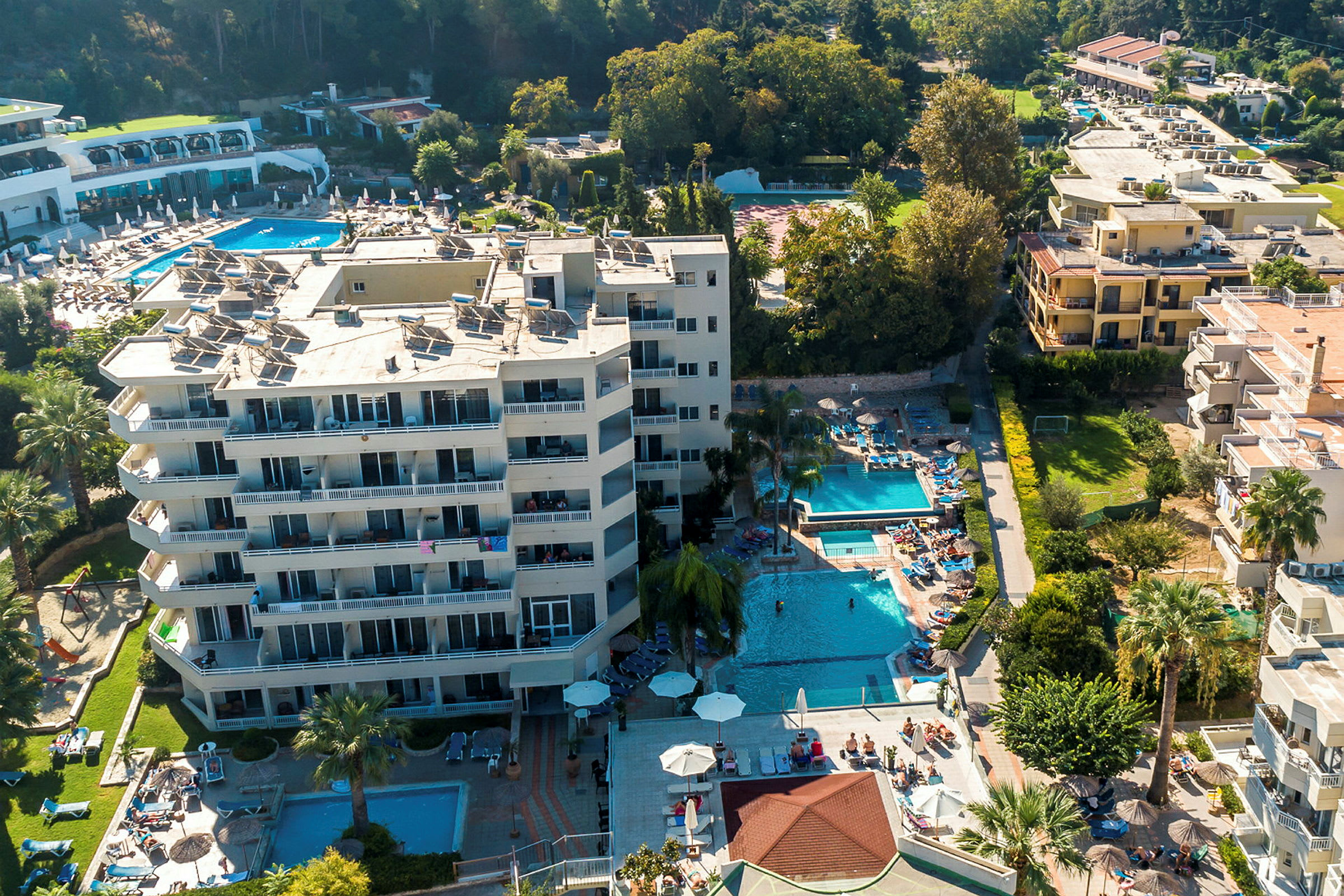 Flygfoto av hotellområde med pooler och solstolar. (AI-genererad text)