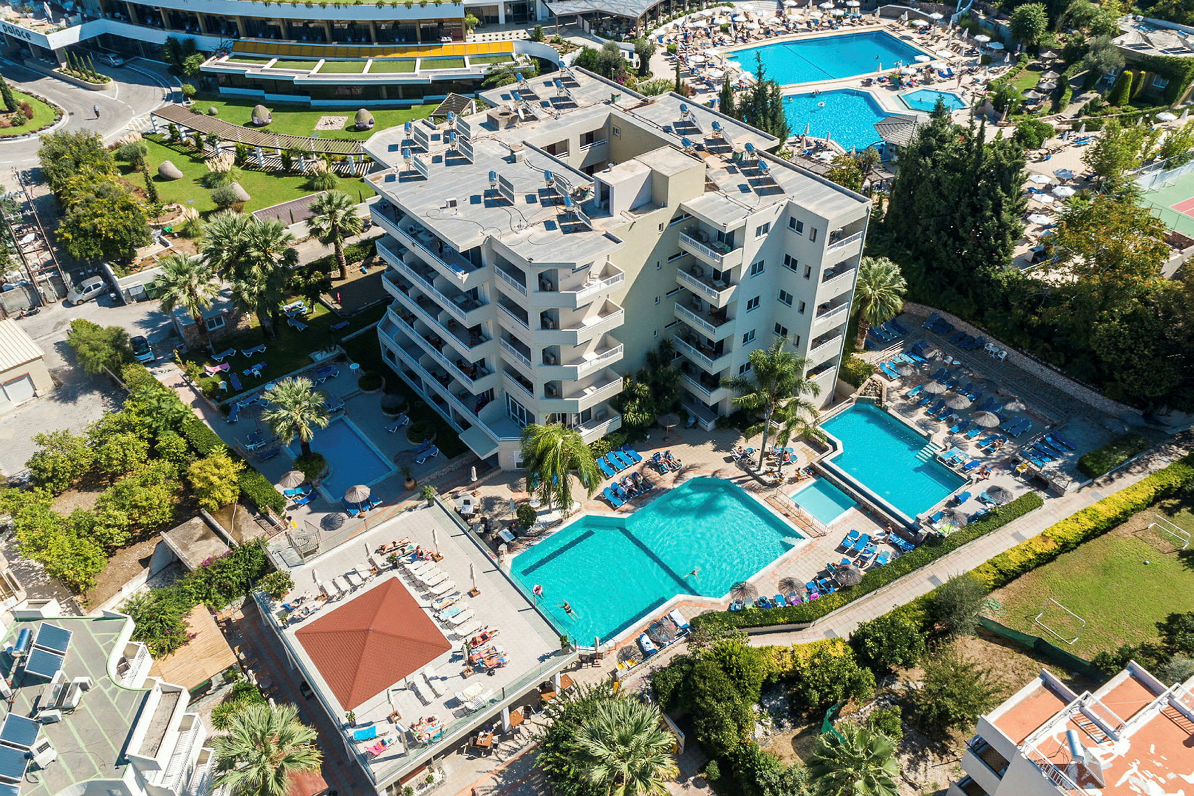 Flygfoto av hotell med poolområden, solstolar och grönska. (AI-genererad text)