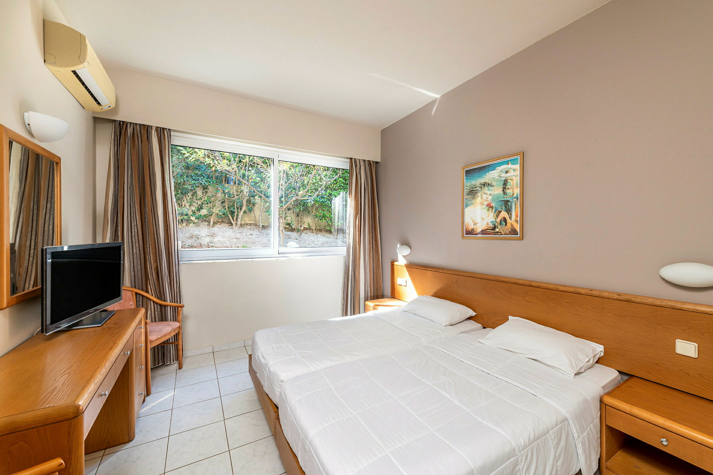 Ett hotellrum med vita väggar, fönster, sängar och möbler. (AI-genererad text)