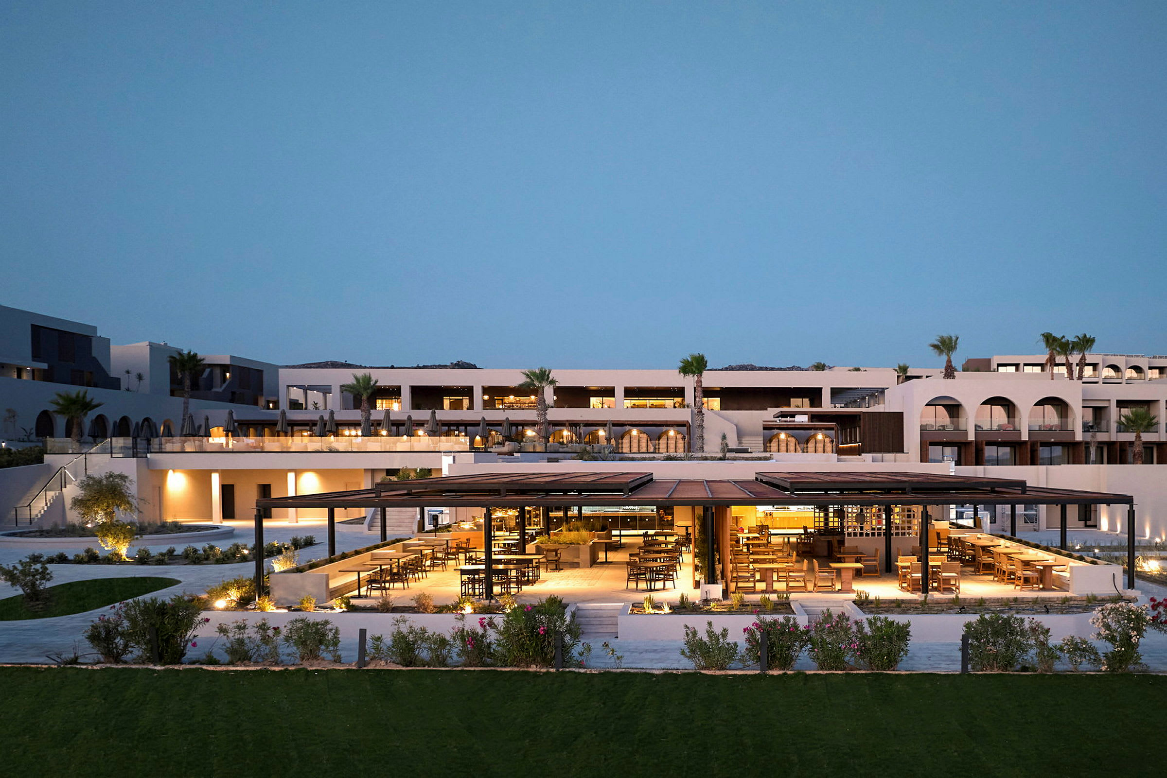 Lyxig resort i modern stil med upplyst utomhusrestaurang och kvällsbelysning. (AI-genererad text)