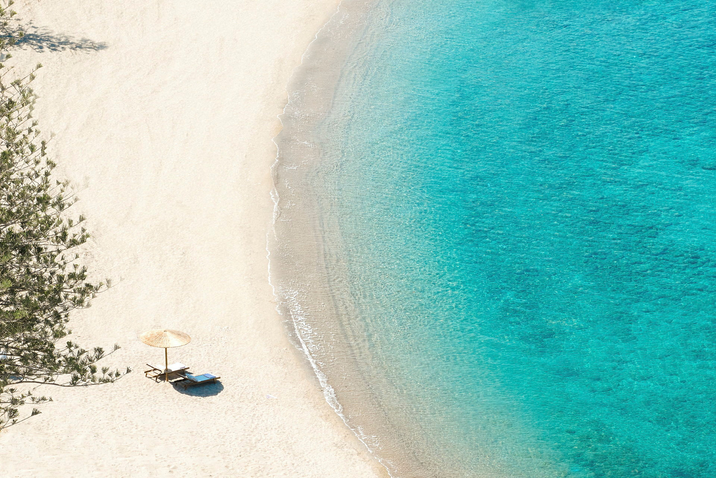 Strand med parasoll och solstolar vid vattenbrynet. (AI-genererad text)