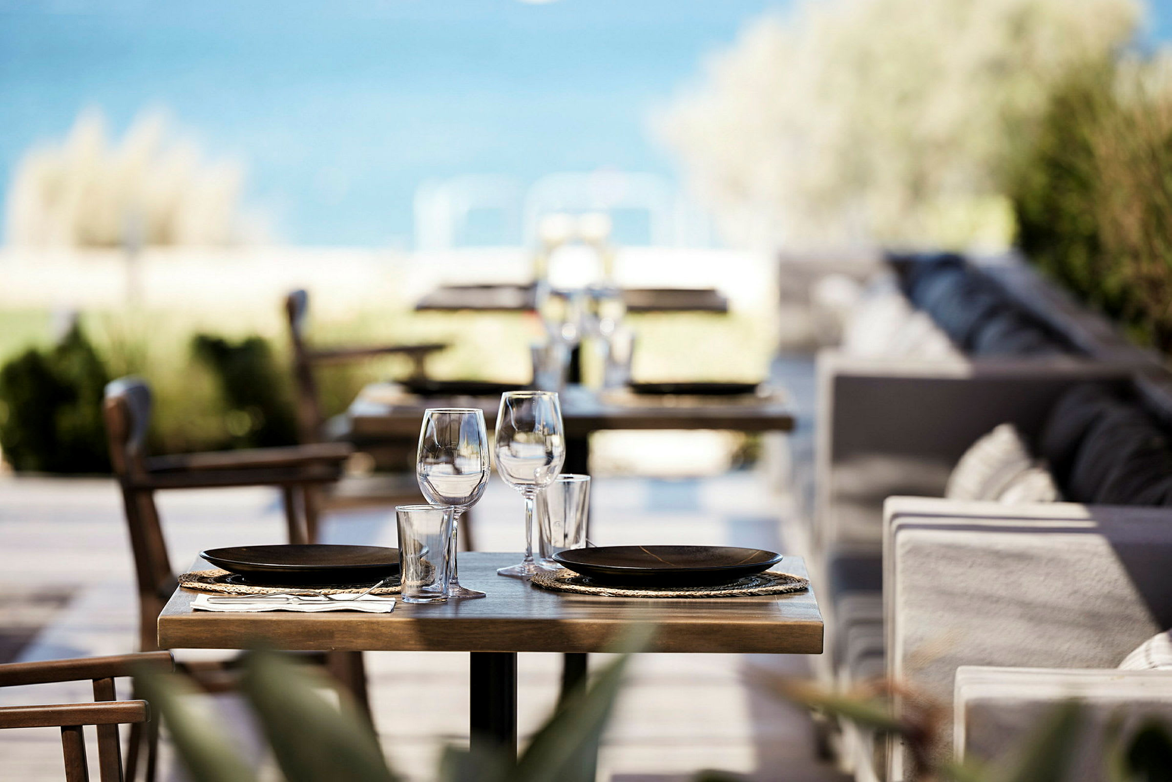 Bild av ett dukat bord på en restaurang med havet i bakgrunden. (AI-genererad text)