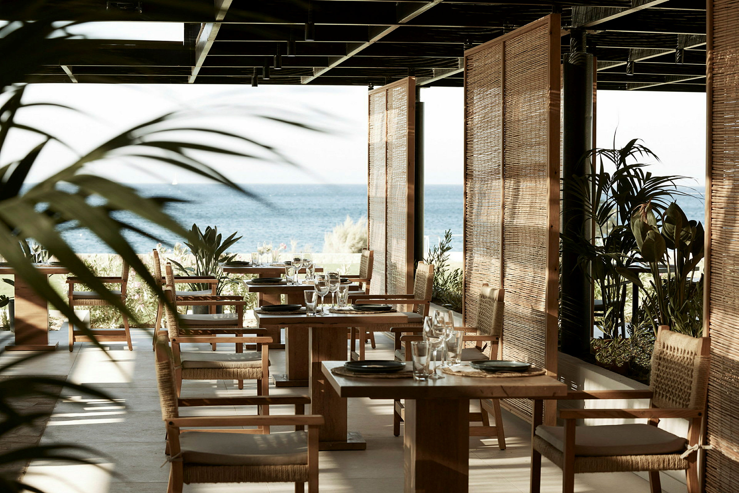 Restaurang med havsutsikt, trästolar och bord. (AI-genererad text)
