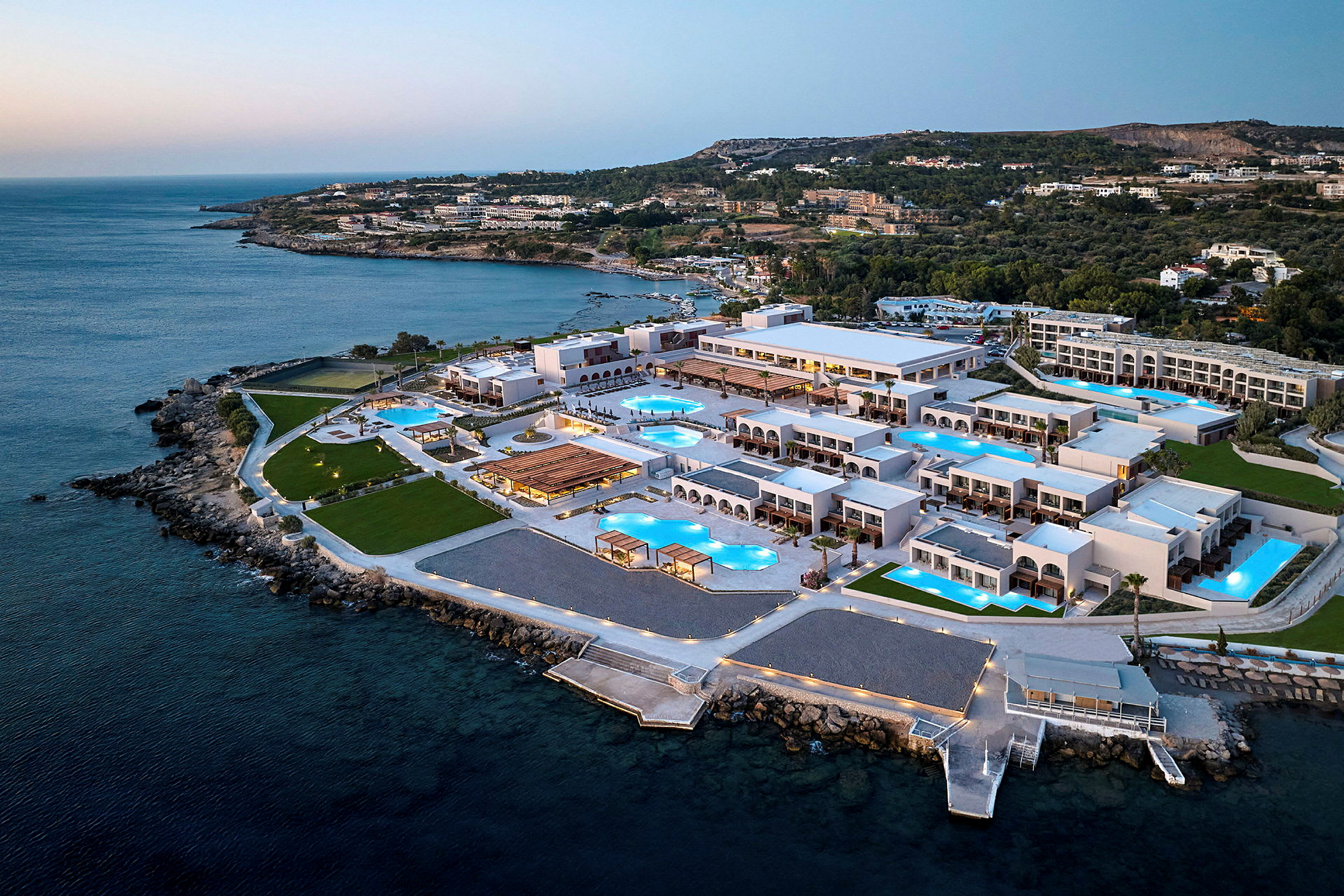 Flygfoto av en resort vid havet med många byggnader och swimmingpooler. (AI-genererad text)