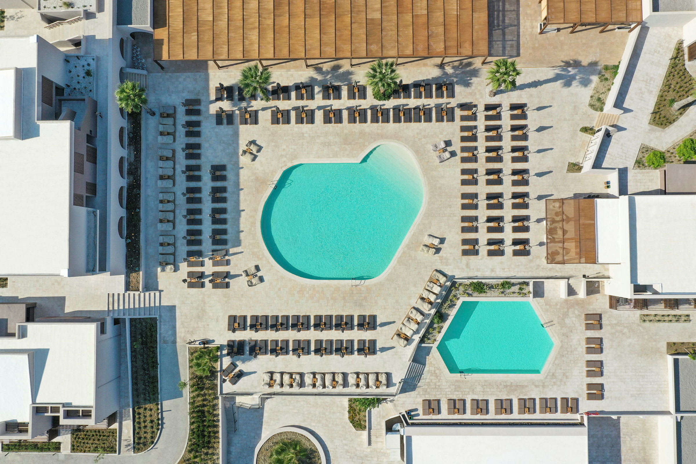 Flygfoto av poolområde vid ett hotell med solsängar omkring. (AI-genererad text)