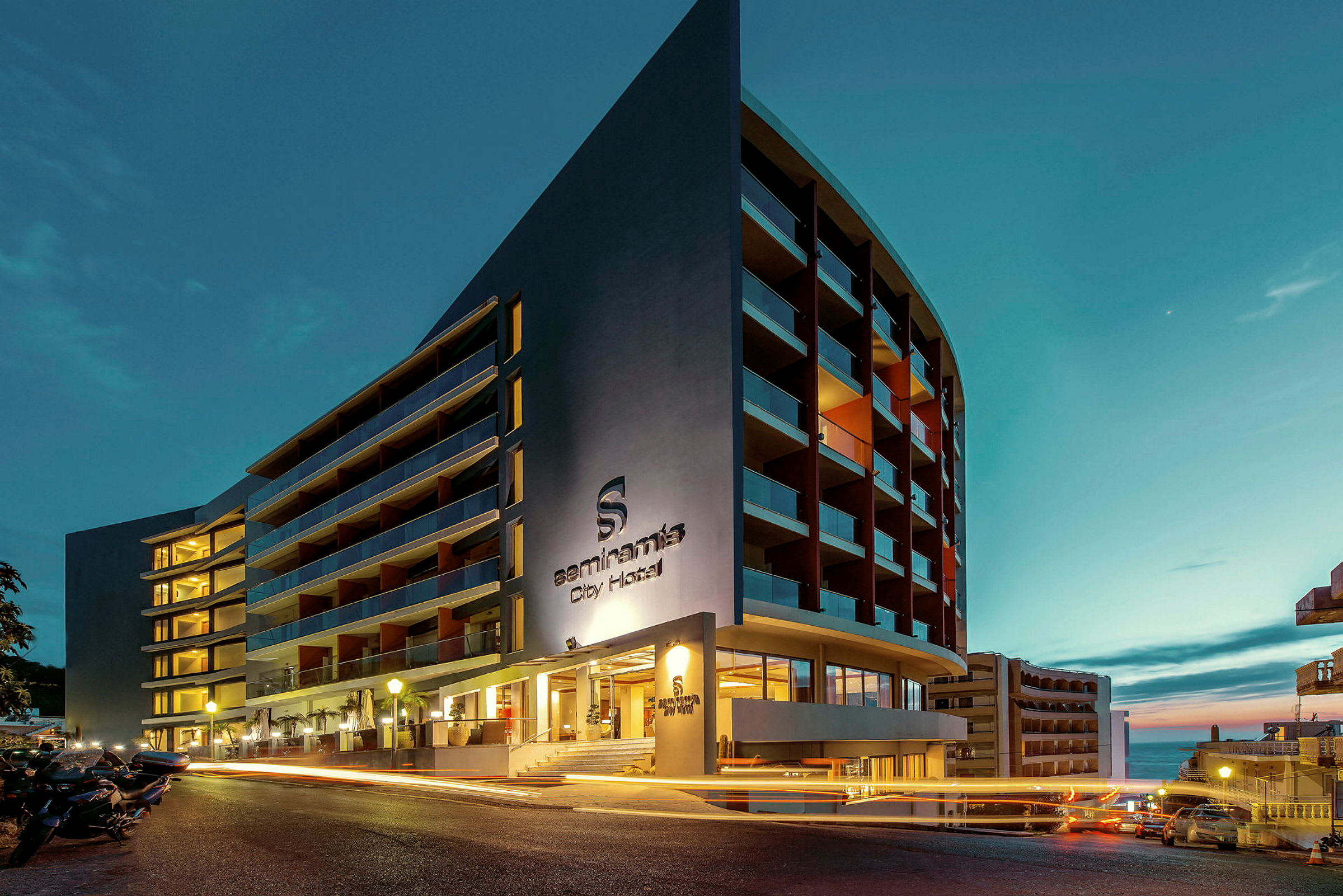 Hotellbyggnad i kvällsljus med belysta fönster och balkonger. (AI-genererad text)