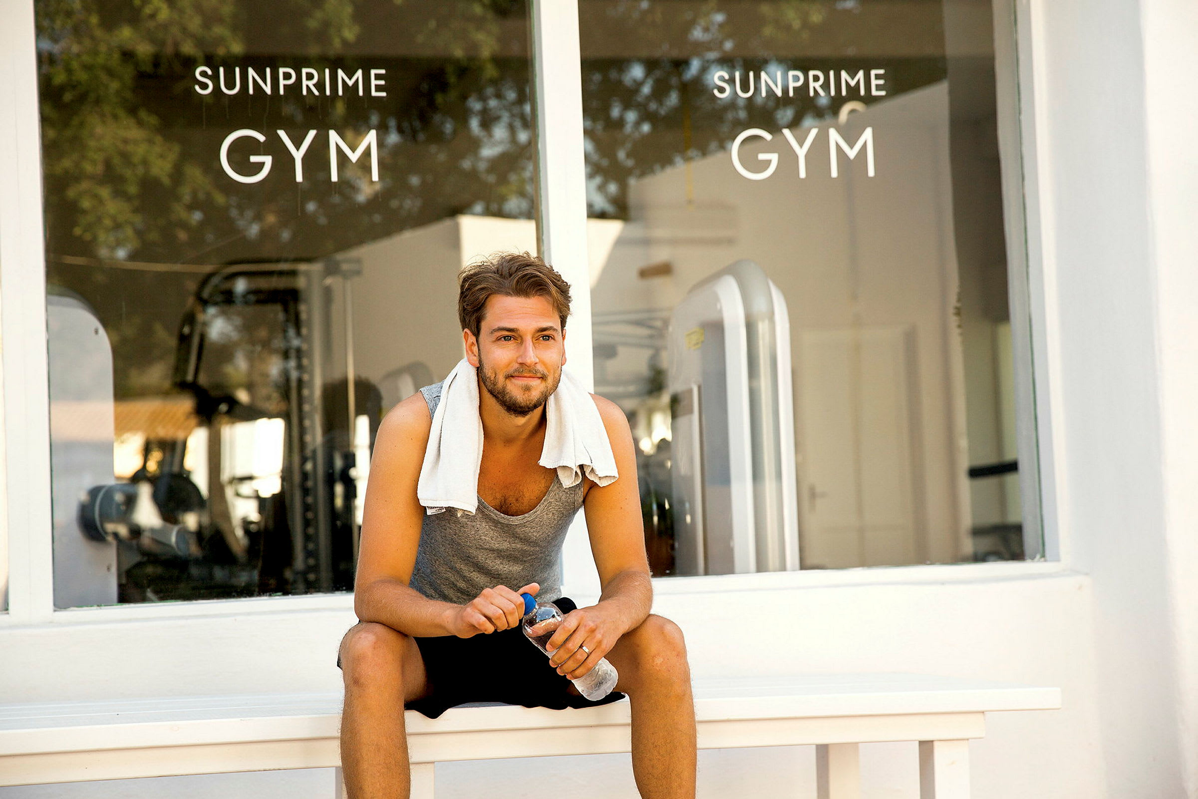 Man som sitter utanför ett gym med interiören synlig genom glaset. (AI-genererad text)