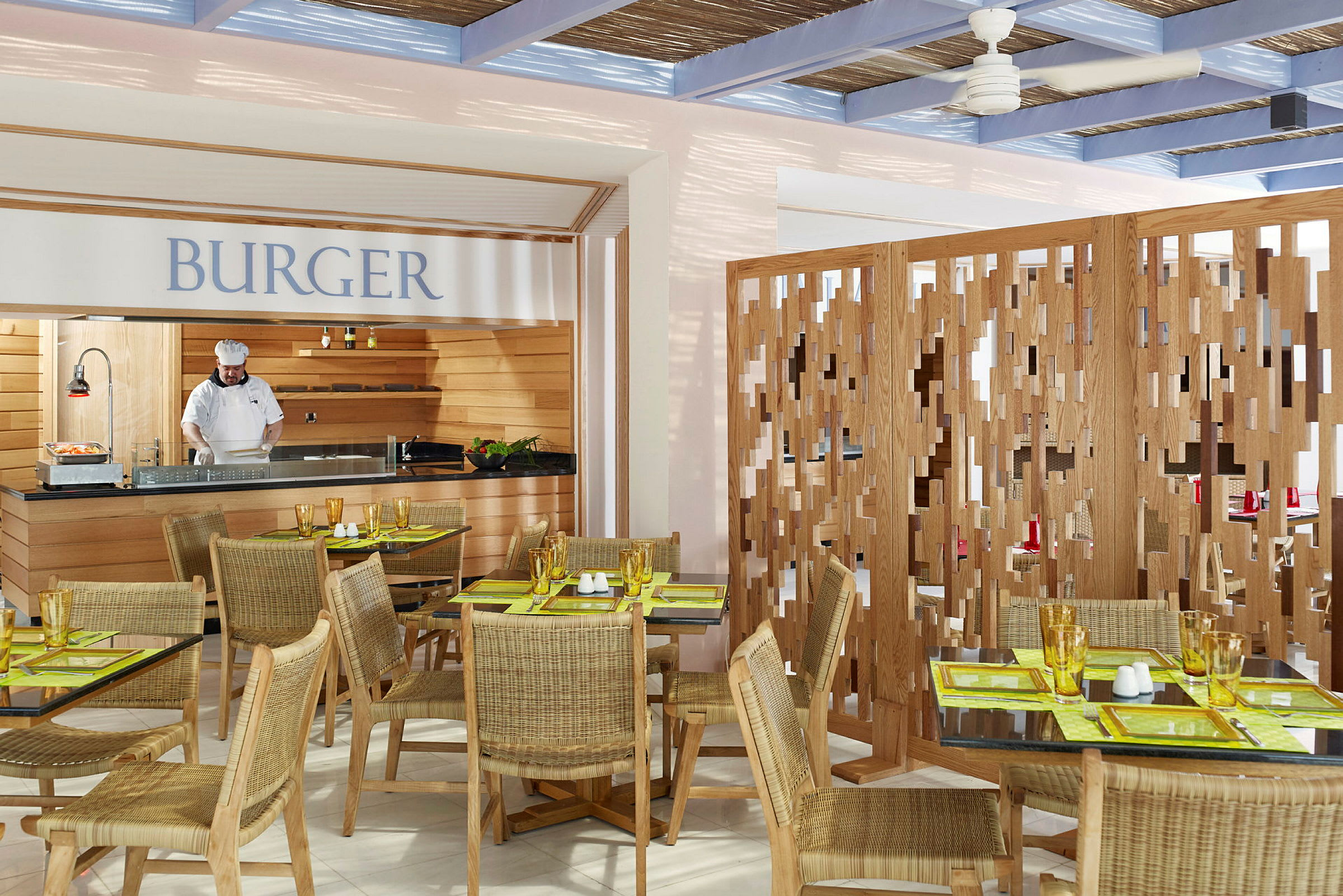 En restauranginteriör med sittplatser, bord och en serveringsstation med texten 'BURGER' ovanför. (AI-genererad text)