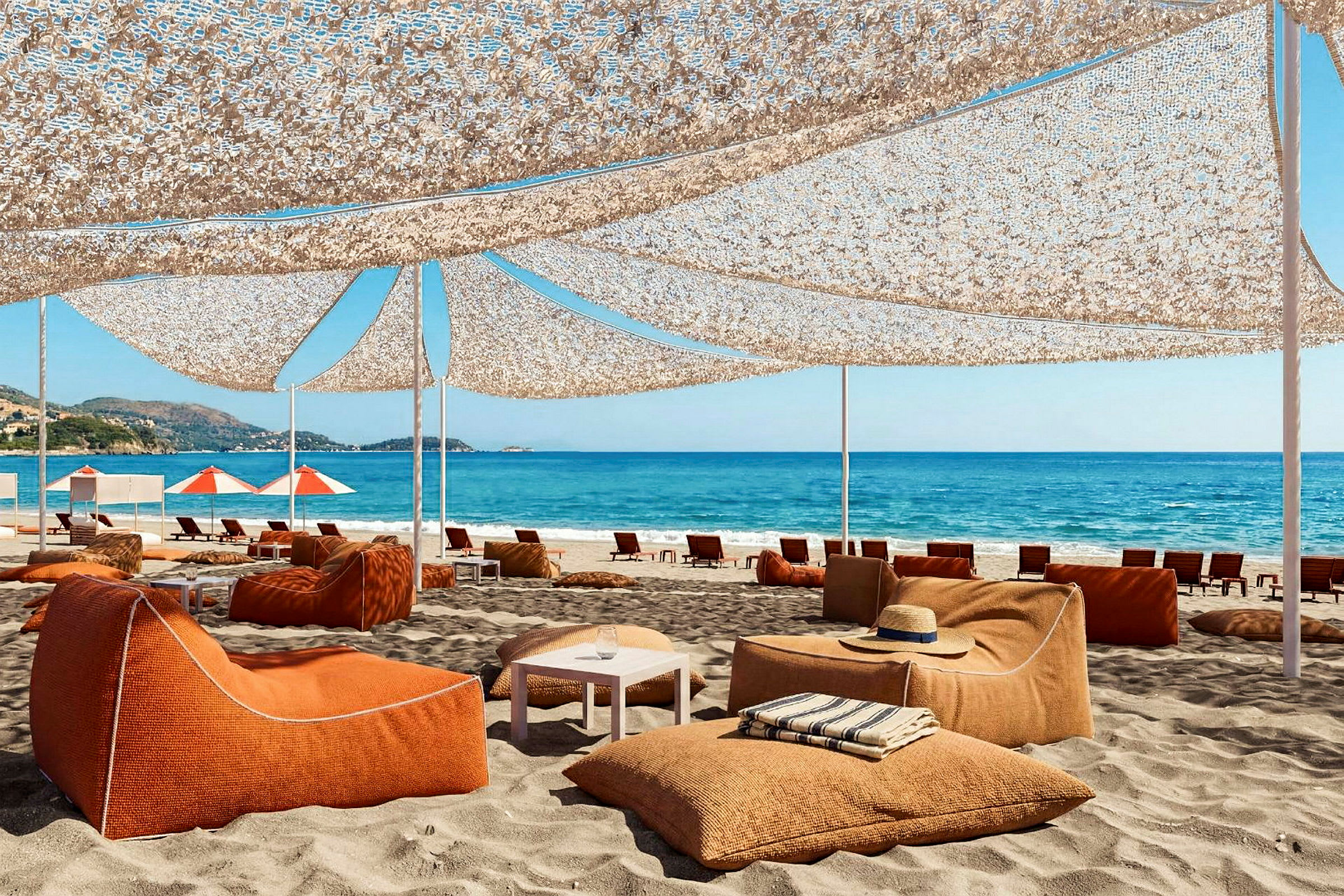 Strand med sittmöbler i orange färg under solskydd. Hav och blå himmel i bakgrunden. (AI-genererad text)