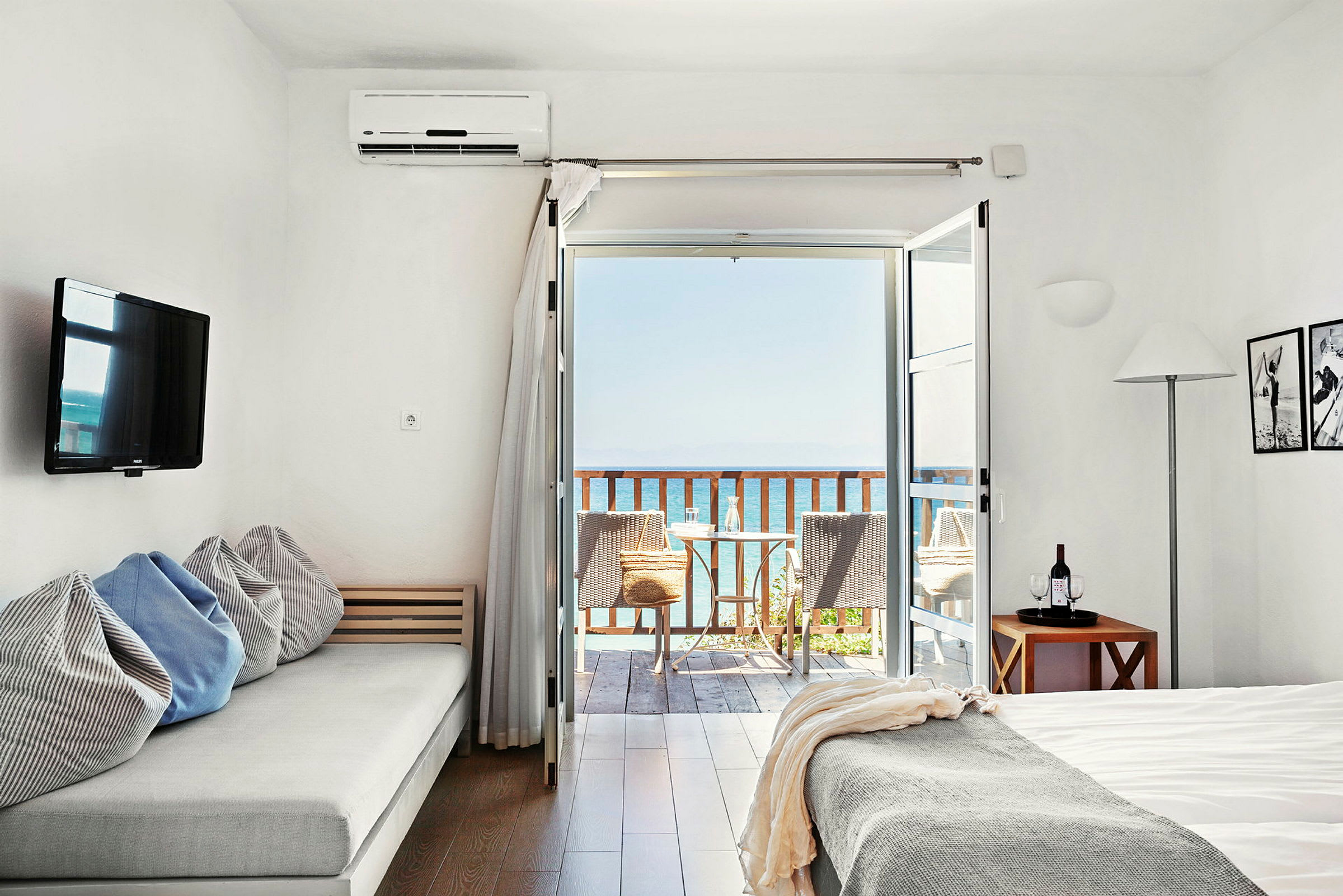 Ett ljust hotellrum med havsutsikt från en balkong. (AI-genererad text)