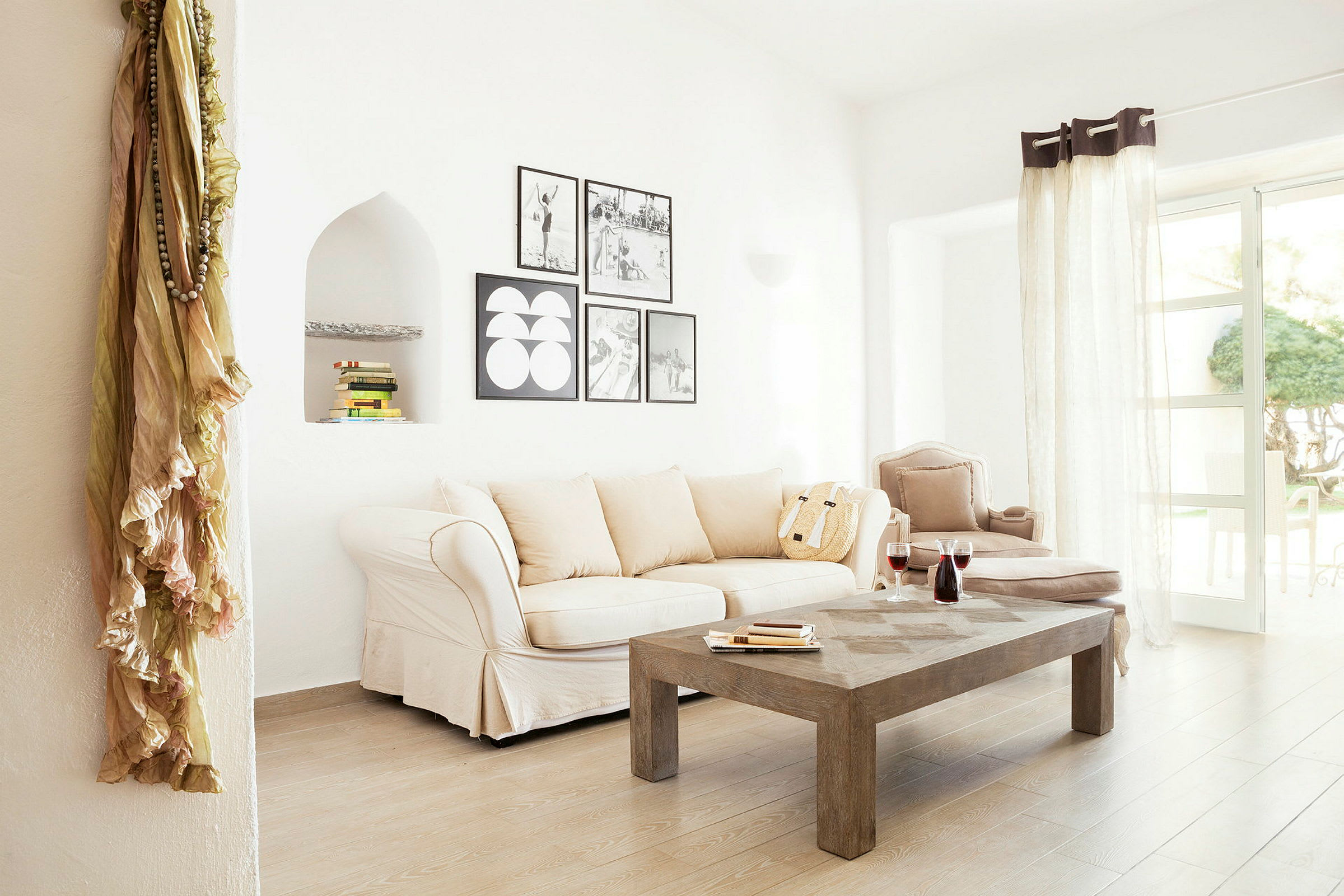 Ett ljust vardagsrum med beige soffa, träbord och dekorativa väggbilder. (AI-genererad text)