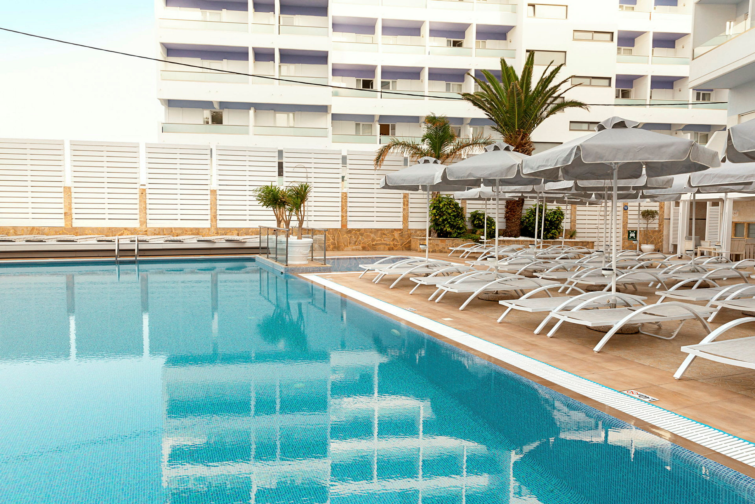 Utomhuspool med solstolar och parasoller i en modern hotellmiljö. (AI-genererad text)