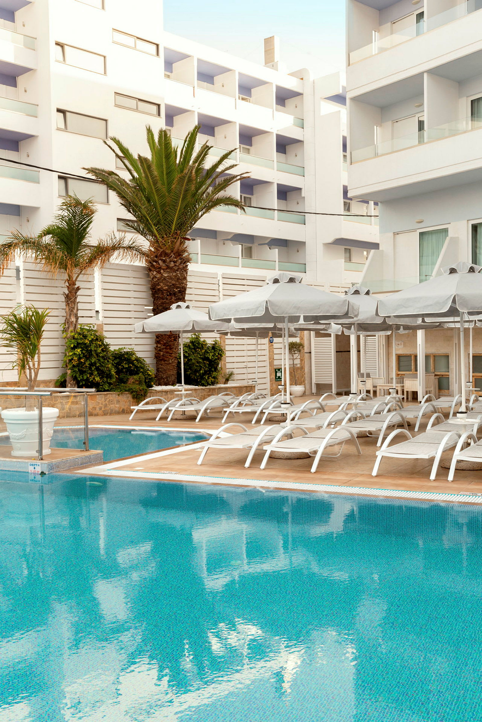 Uteplats med pool, solstolar och parasoller vid ett hotell. (AI-genererad text)