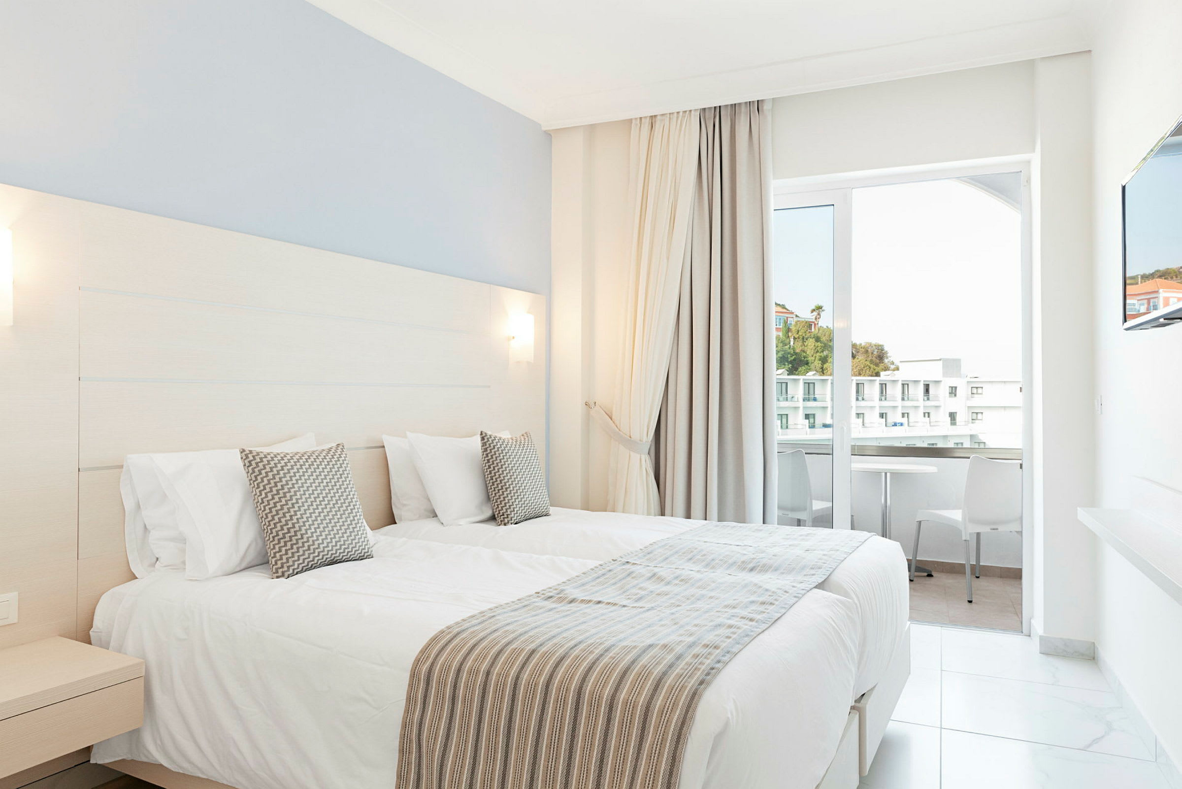 Hotelrum med två enkelsängar och balkong. (AI-genererad text)