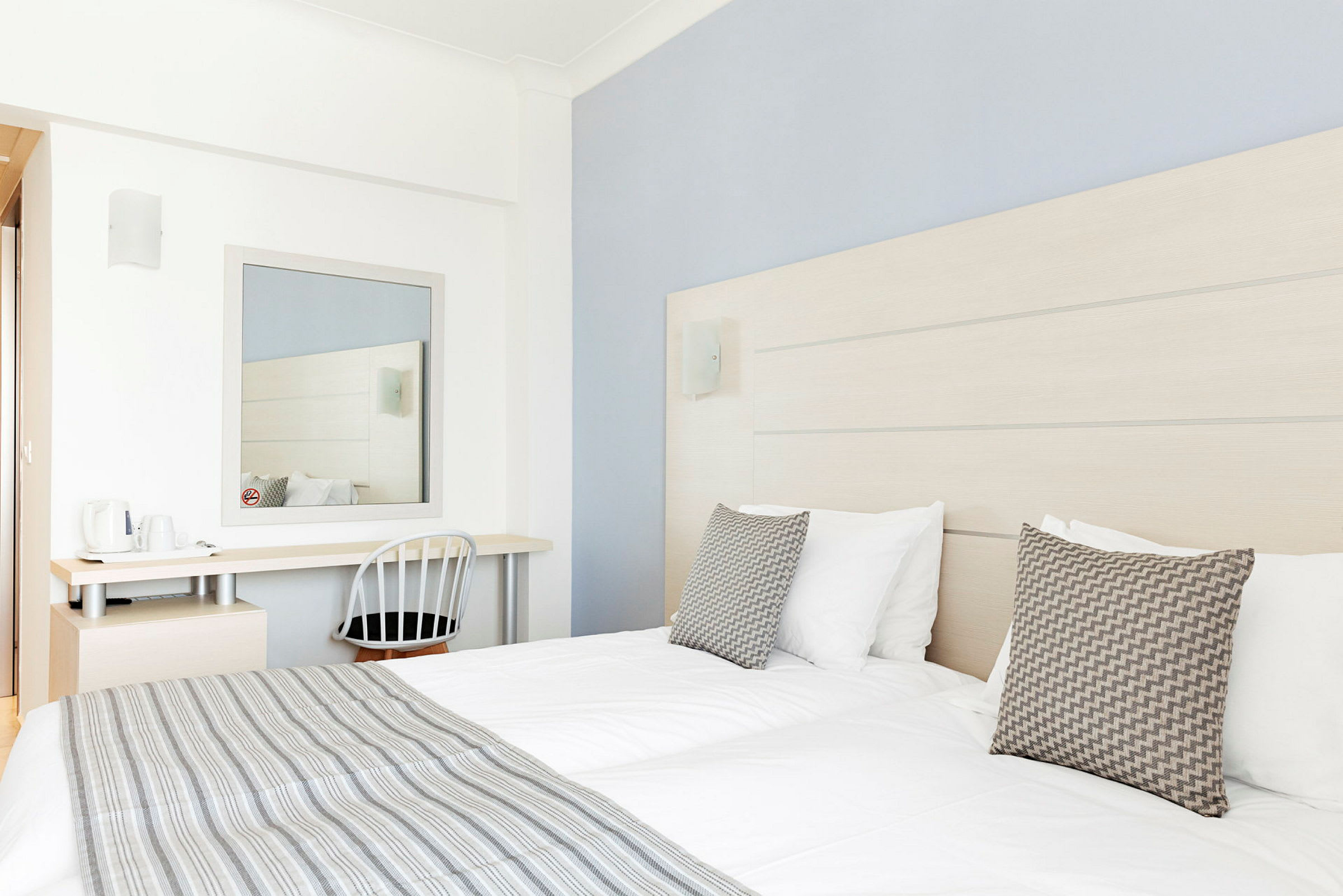 Ett hotellrum med två sängar, ett skrivbord och en spegel. (AI-genererad text)
