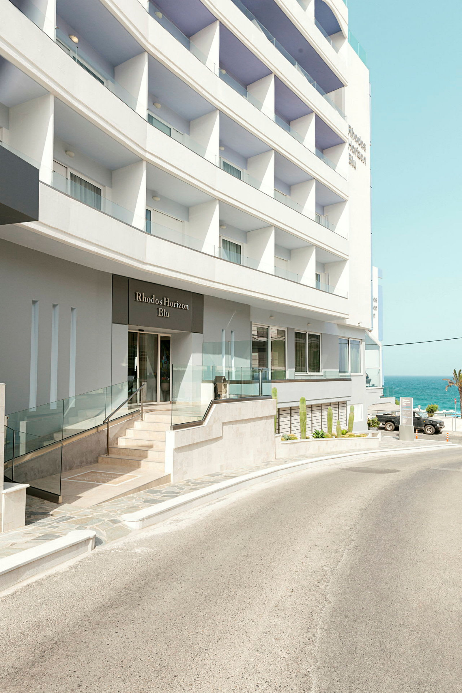 Hotellbyggnad med entré och utsikt mot havet. (AI-genererad text)