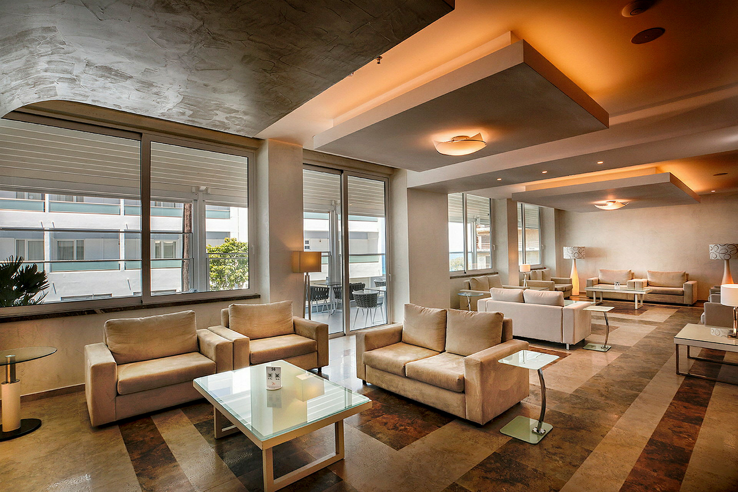 Modernt inrett hotellfoajé med beige soffor och glasbord. (AI-genererad text)