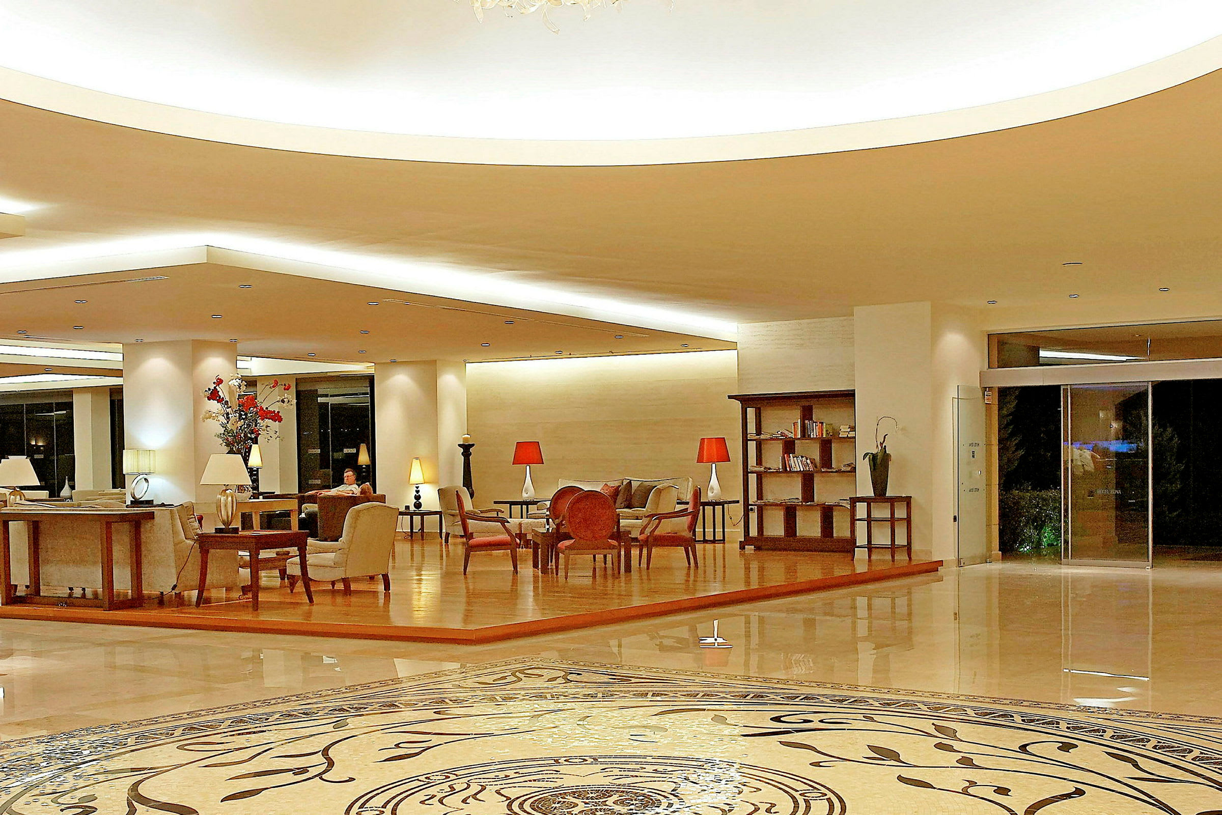 Ett hotellobbyområde med sittgrupper och dekorativa möbler. En man sitter i bakgrunden. (AI-genererad text)