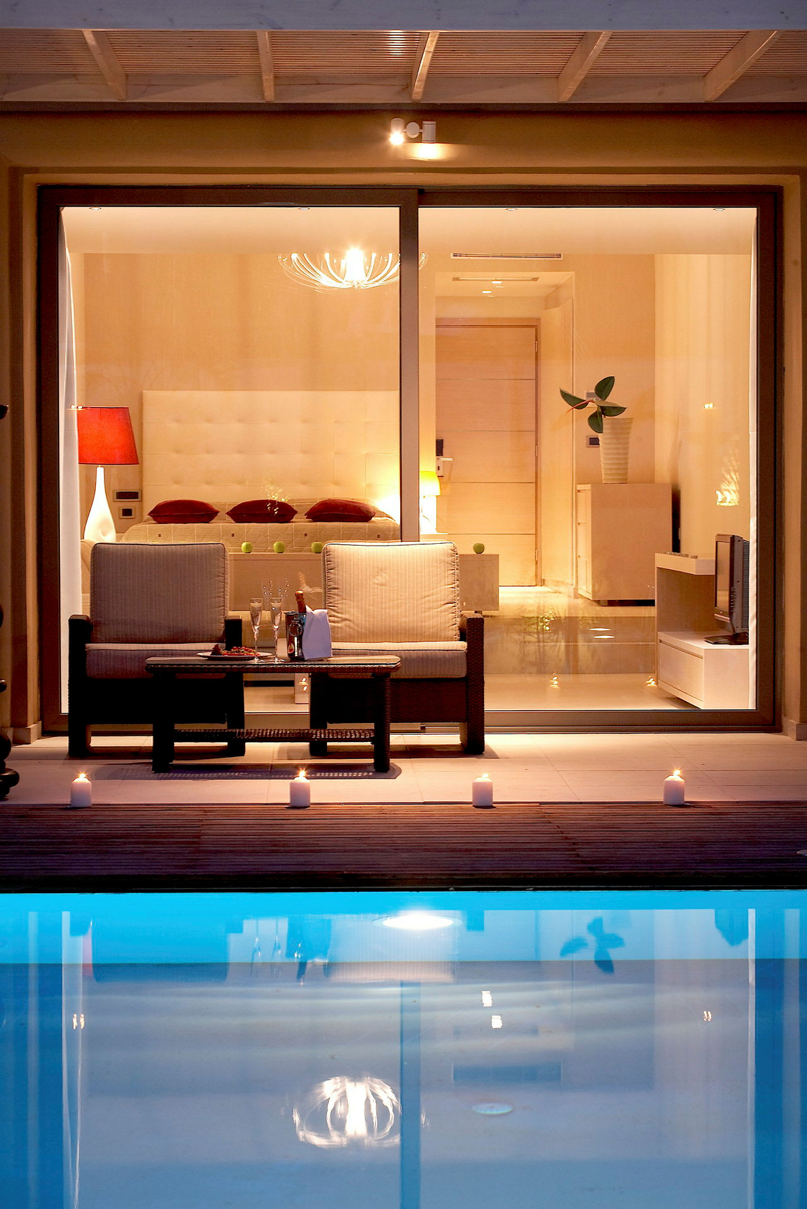 Modern och elegant inrett rum med sittplatser framför en klarblå pool. (AI-genererad text)