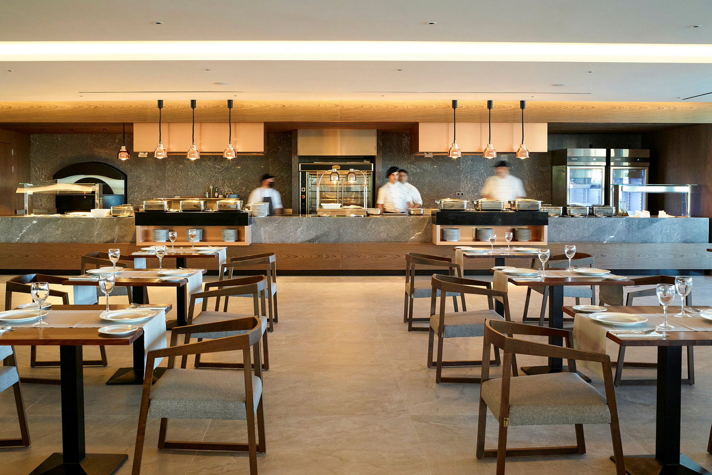En modern restaurang med dukade bord, stolar och ett öppet köksområde. (AI-genererad text)