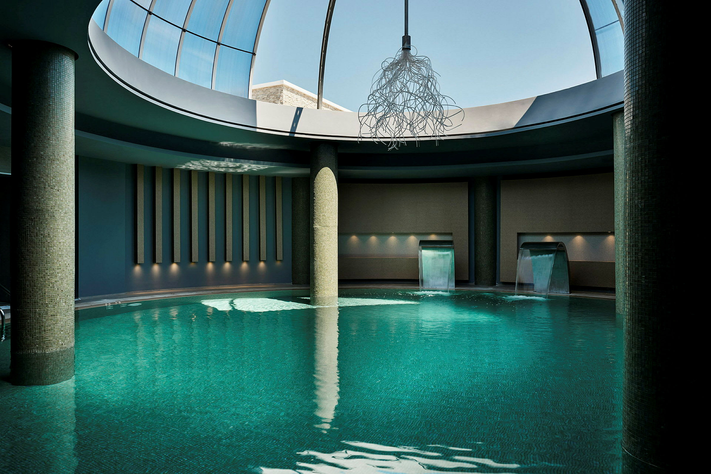Inomhuspool med vattenfall och modern belysning. (AI-genererad text)