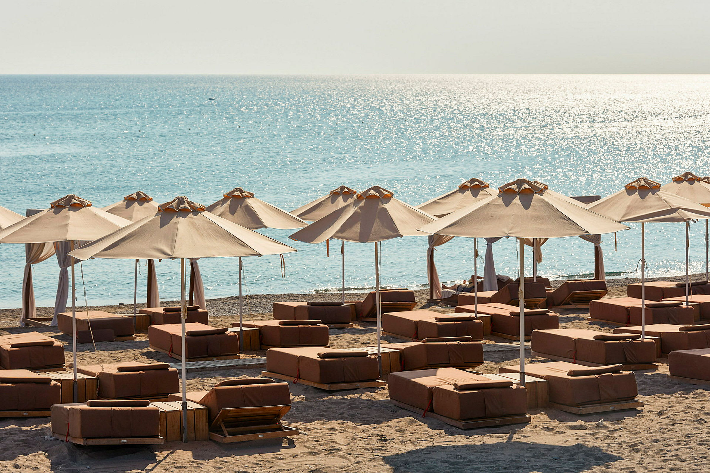 Solstolar och parasoller på en sandstrand med havet i bakgrunden. (AI-genererad text)