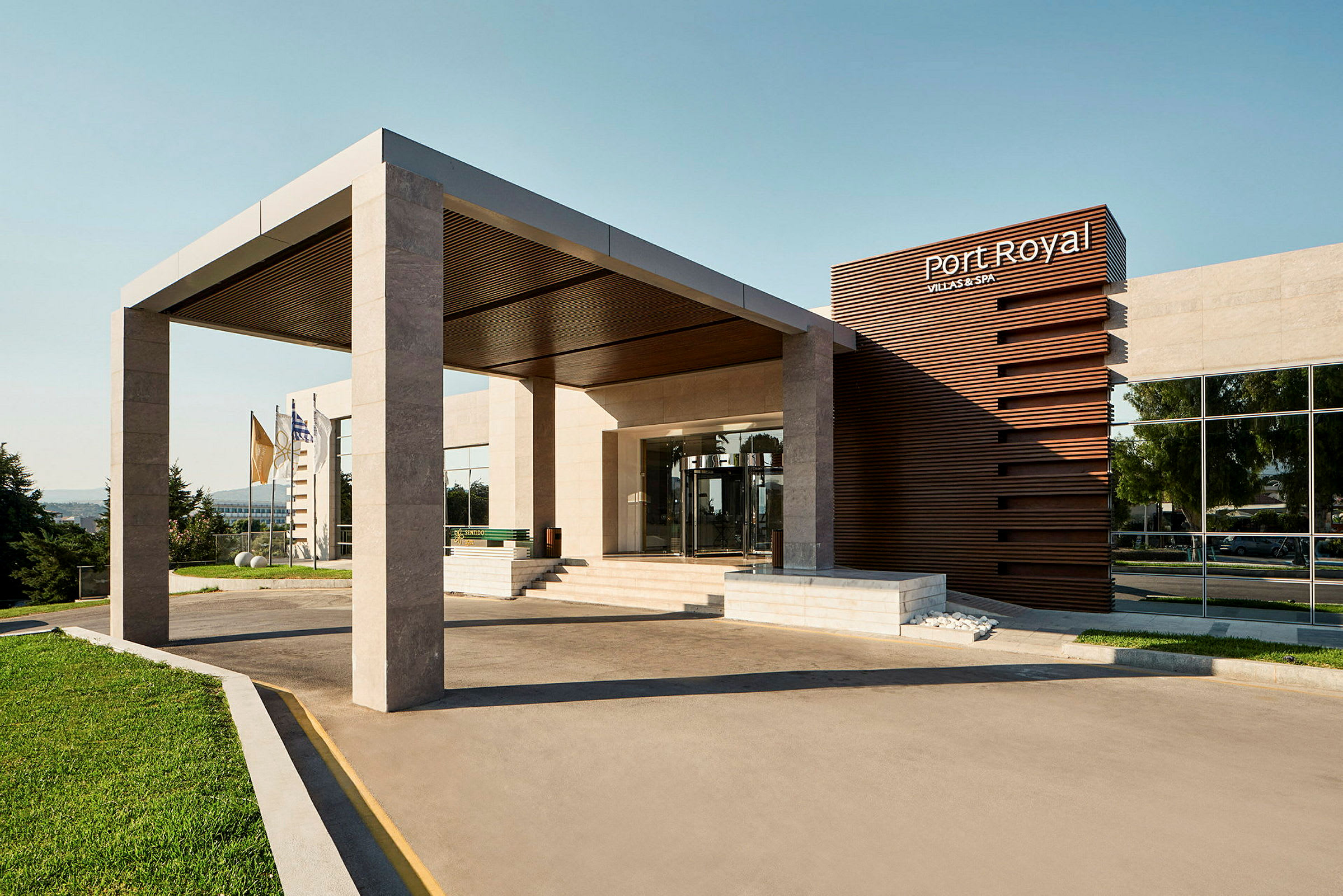 Entré till en modern byggnad med skylt för 'Port Royal Villas & Spa' och flaggor i bakgrunden. (AI-genererad text)