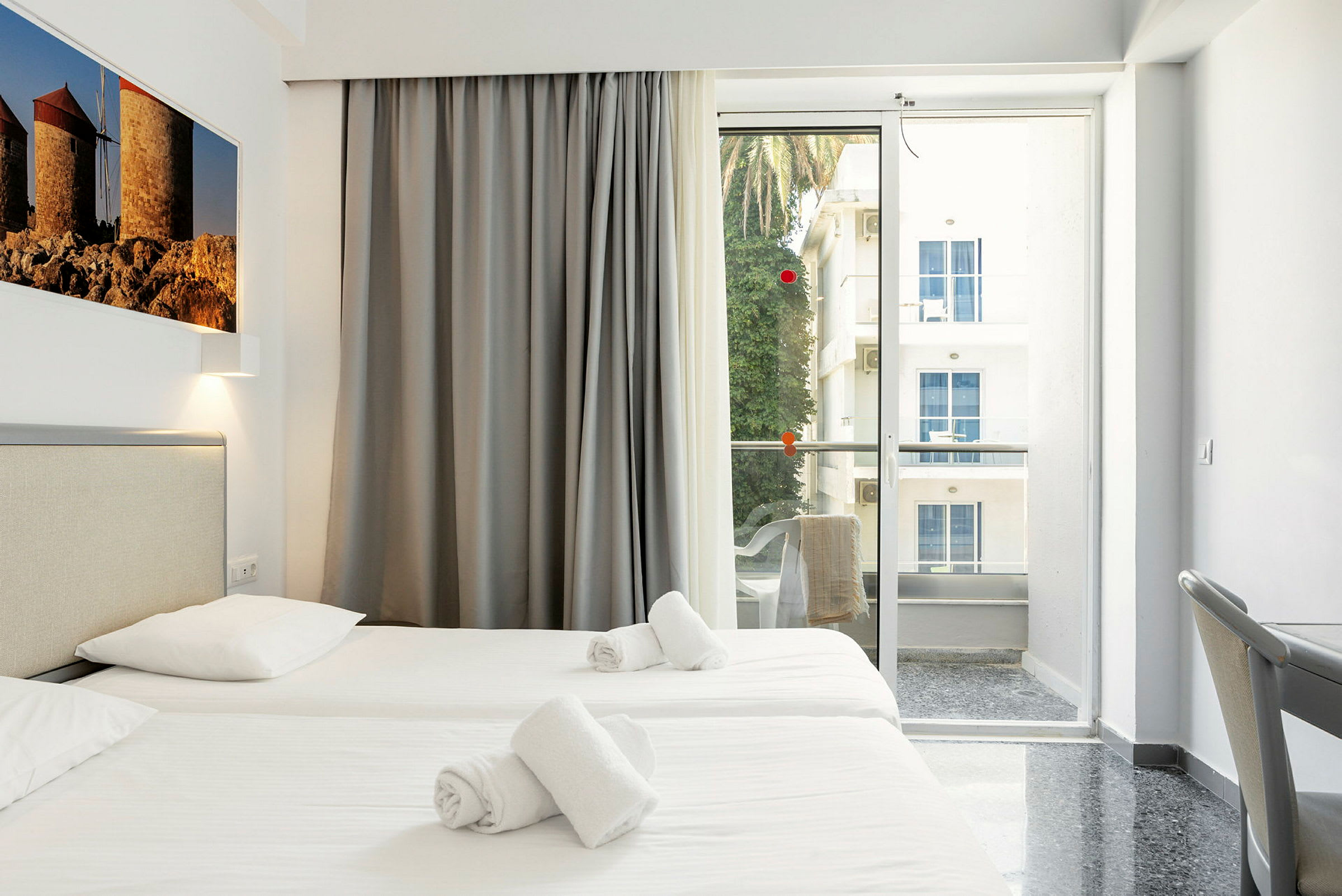 Hotellrum med två enkelsängar, balkong med utsikt. (AI-genererad text)
