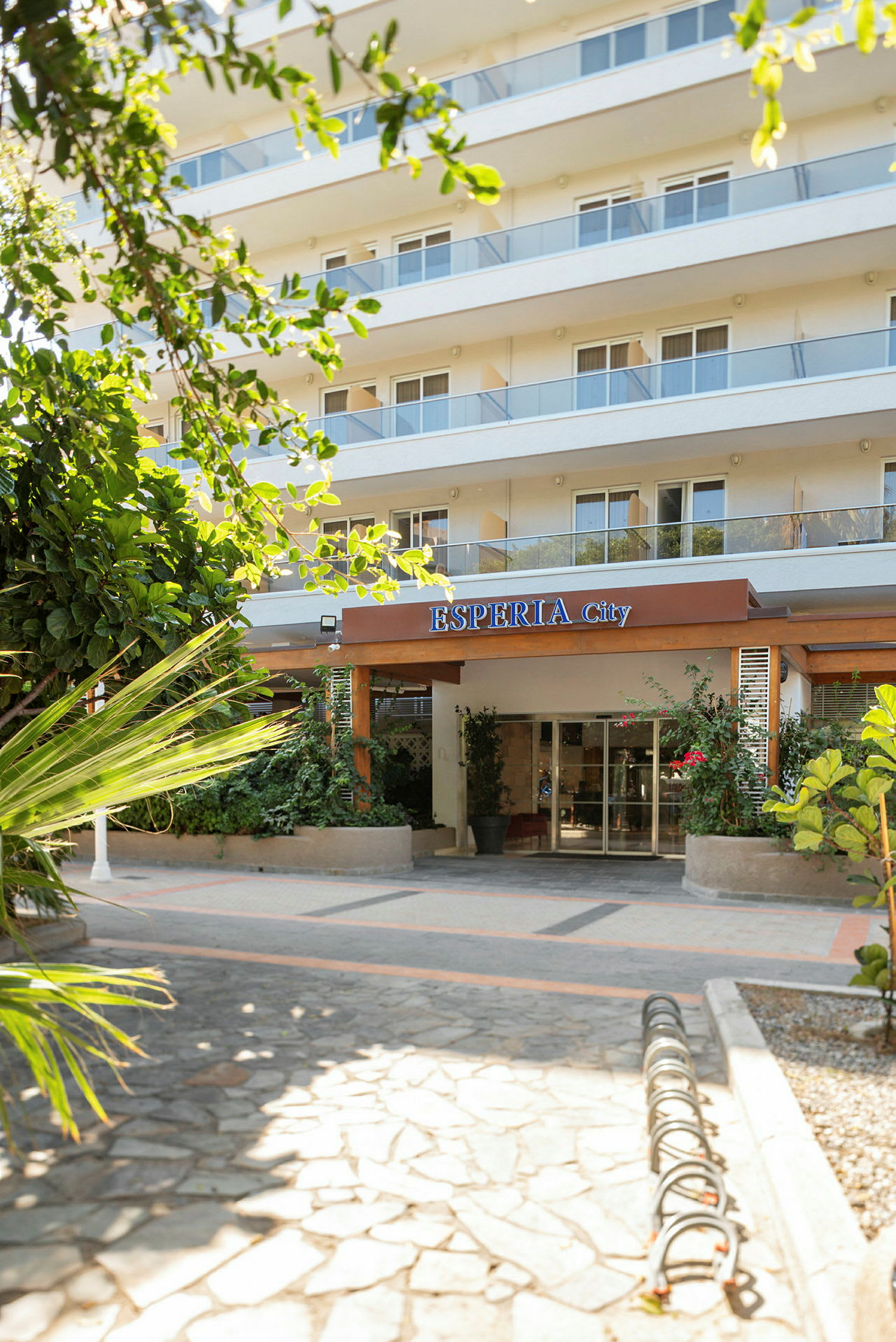 Entrén till ett flerfaldig hotell med gröna växter i förgrunden. (AI-genererad text)