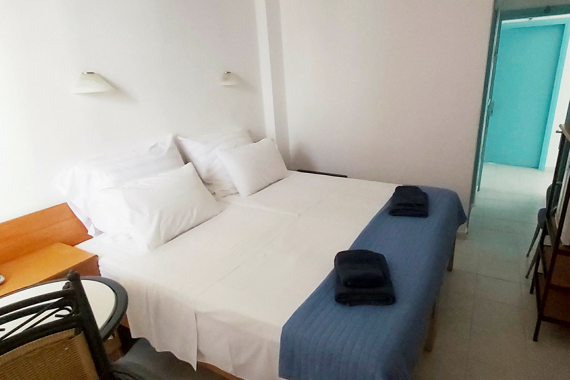Ett hotellrum med två bäddar, vita lakan och blåa överkast. (AI-genererad text)