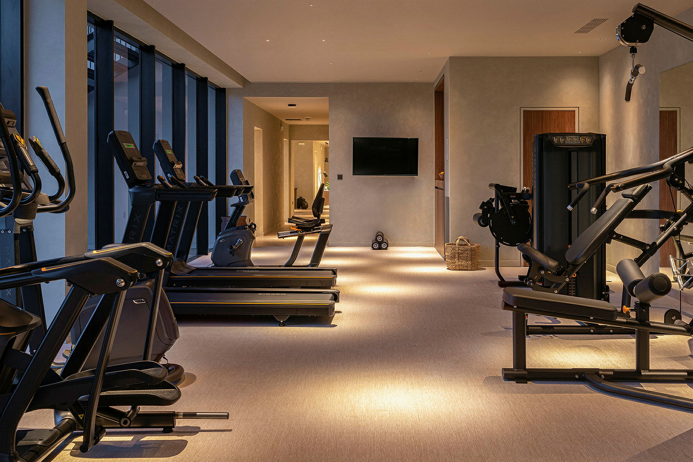 Ett modernt gym med träningsmaskiner och stora fönster. (AI-genererad text)