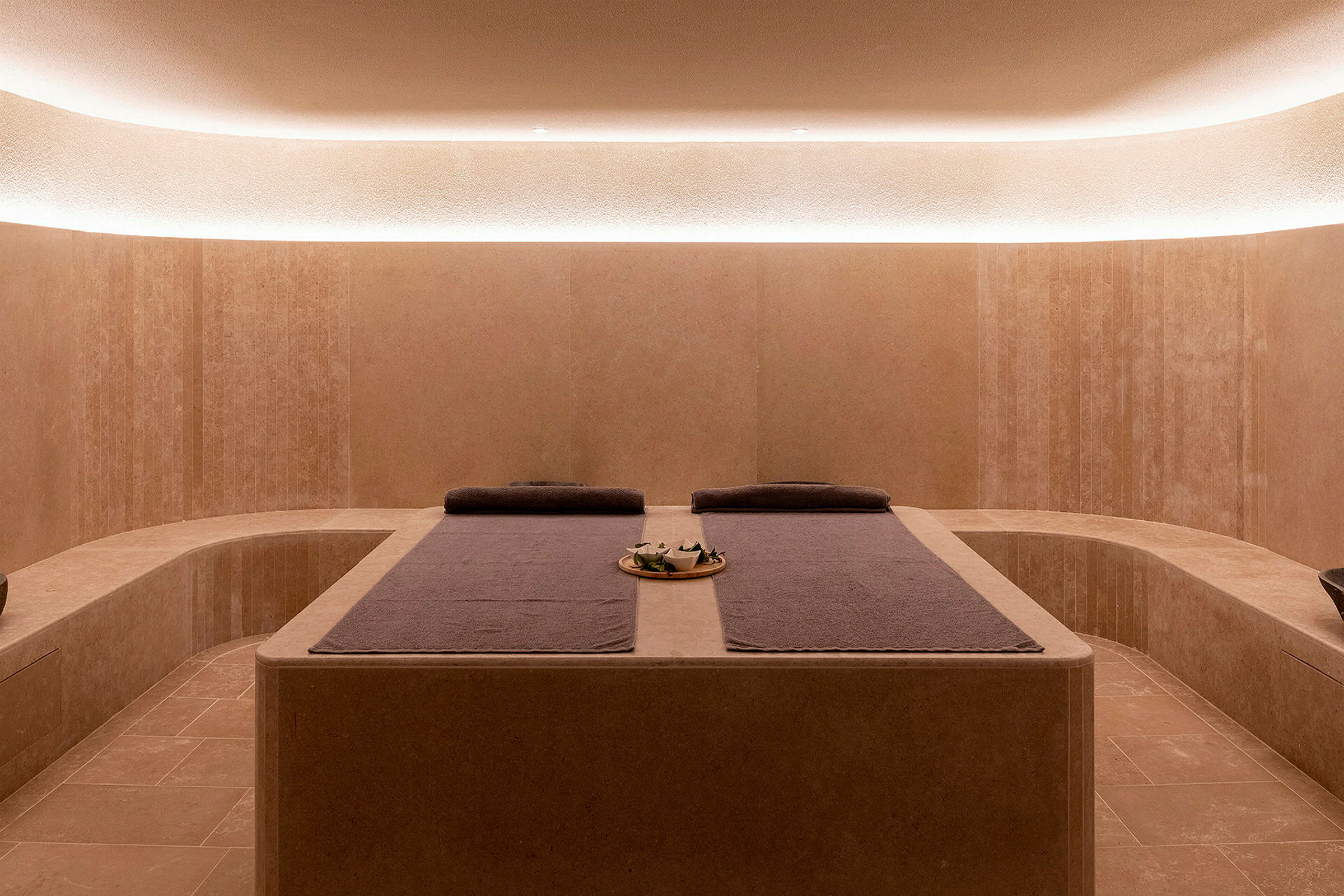 Ett modernt spa-rum med avkopplande belysning och två massagebäddar med handdukar. (AI-genererad text)