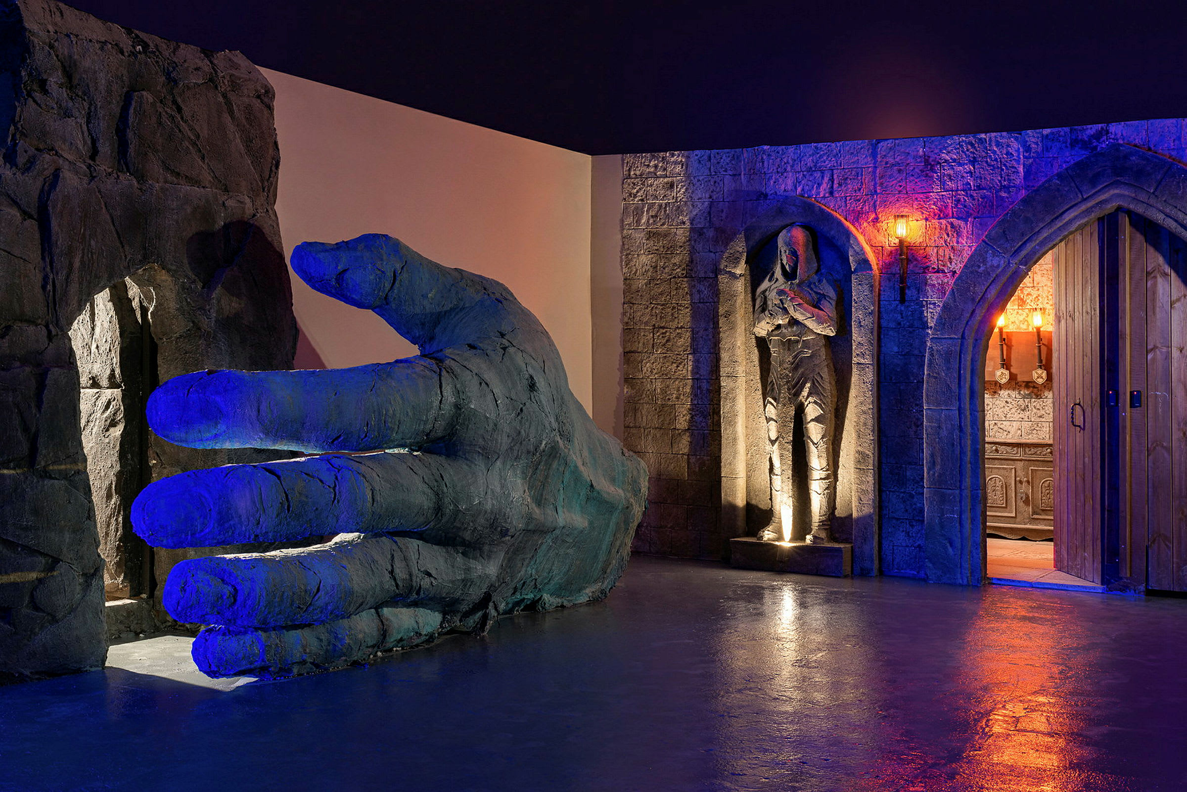 En stor konstgjord hand med en skulptur av en person i en rock bredvid en gotisk dörr. (AI-genererad text)