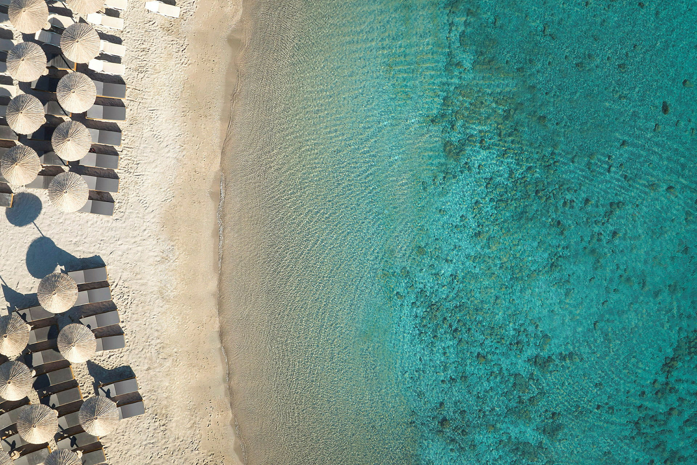 Strand med solstolar och parasoller bredvid turkost hav. (AI-genererad text)