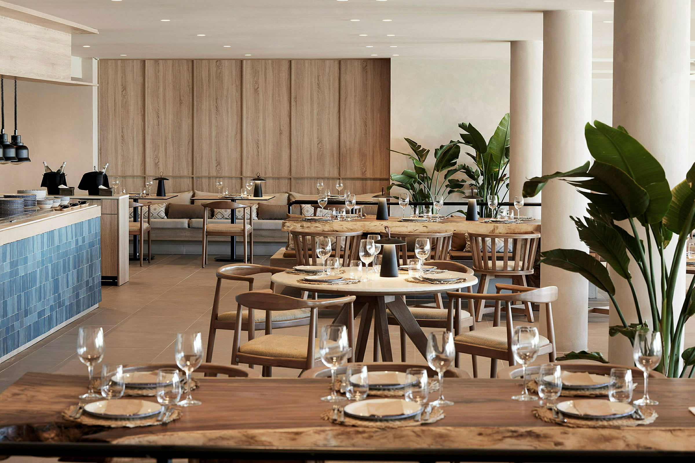 En modern restaurang med träbord, stolar och dekorativ gröna växter. (AI-genererad text)