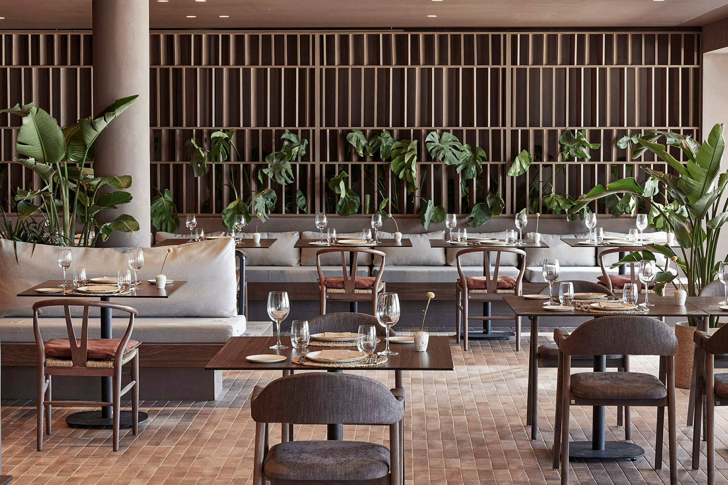 Restaurang med dukade matbord, moderna möbler och gröna växter. (AI-genererad text)