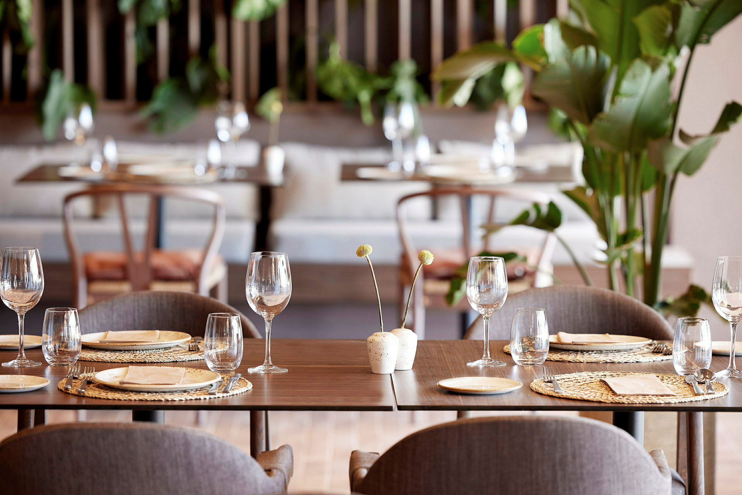 Interiör av en modern restaurang med dukade bord, glas och växter. (AI-genererad text)