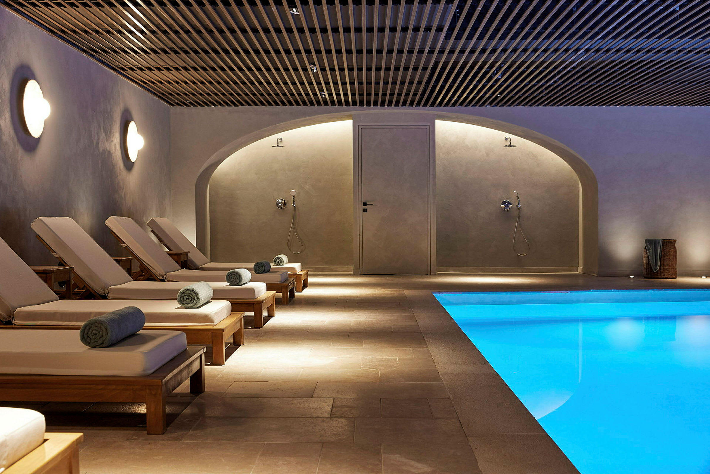 Interiörbild av ett spa med solstolar och en swimmingpool. (AI-genererad text)