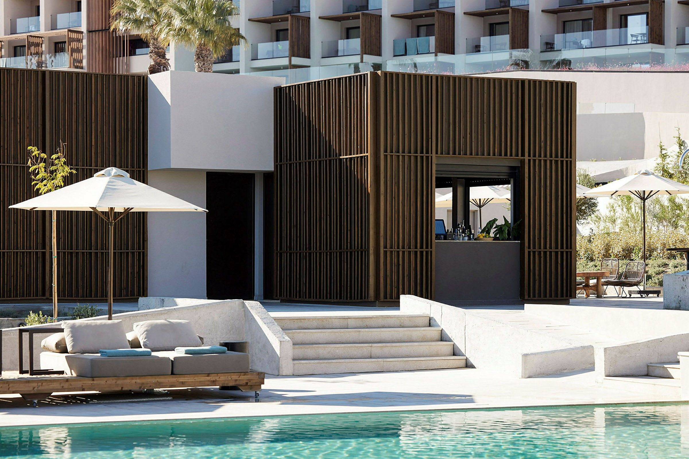 Bild av en modern hotellbar vid en pool med solstolar och parasoller. (AI-genererad text)