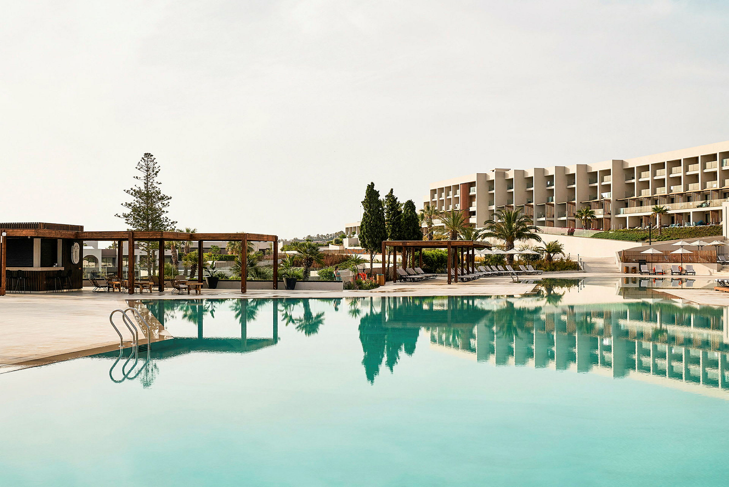 Utomhuspool med solstolar och utsikt över hotellbyggnader. (AI-genererad text)