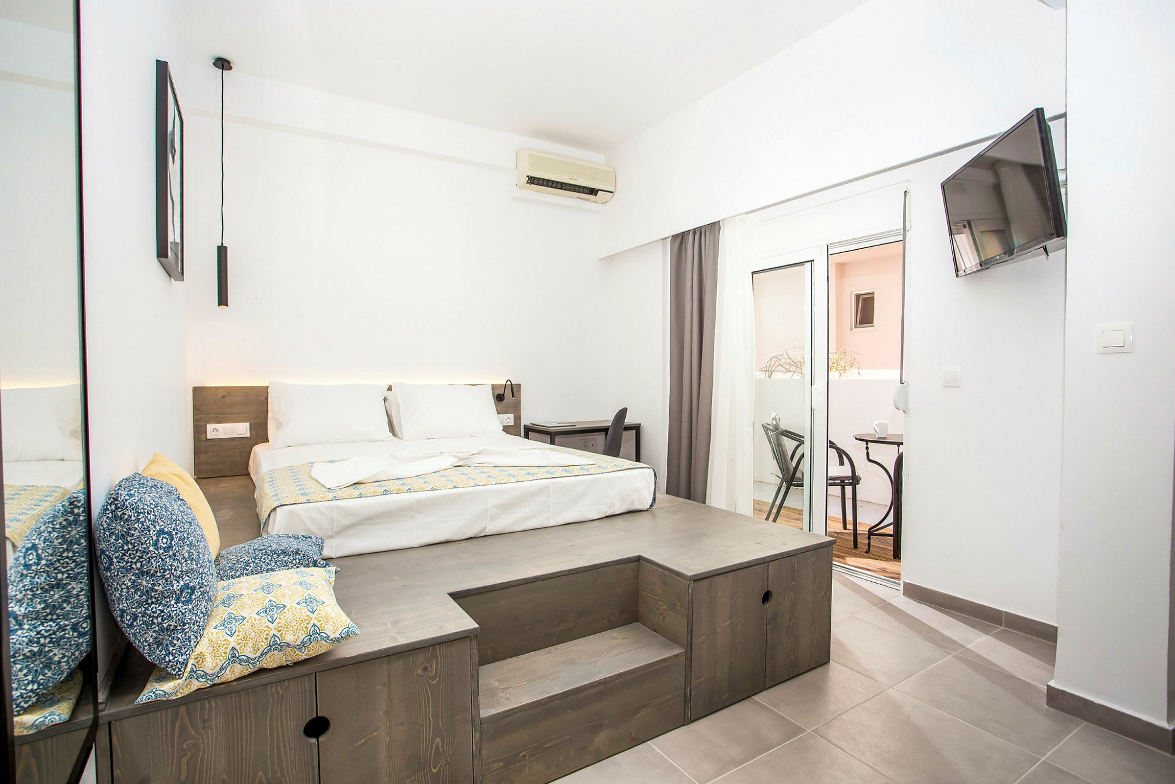 Ett modernt hotellrum med en stor säng, en sittplats med kuddar och en balkong. (AI-genererad text)
