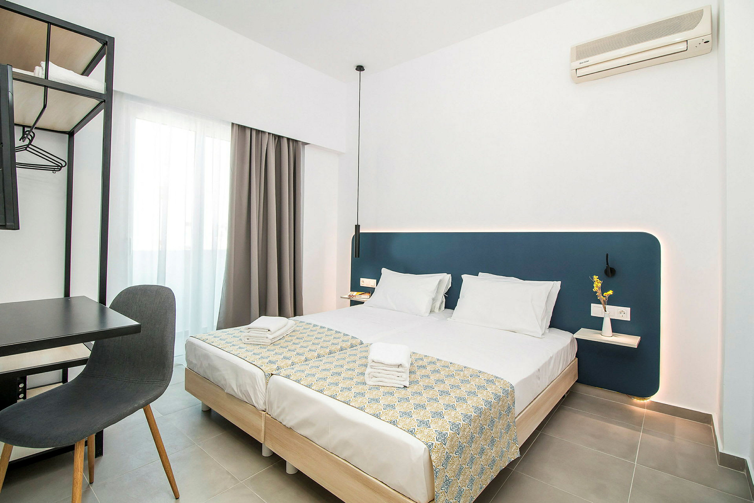 Modernt hotellrum med två bäddade enkelsängar, skrivbord och stol samt väggmonterad luftkonditionering. (AI-genererad text)