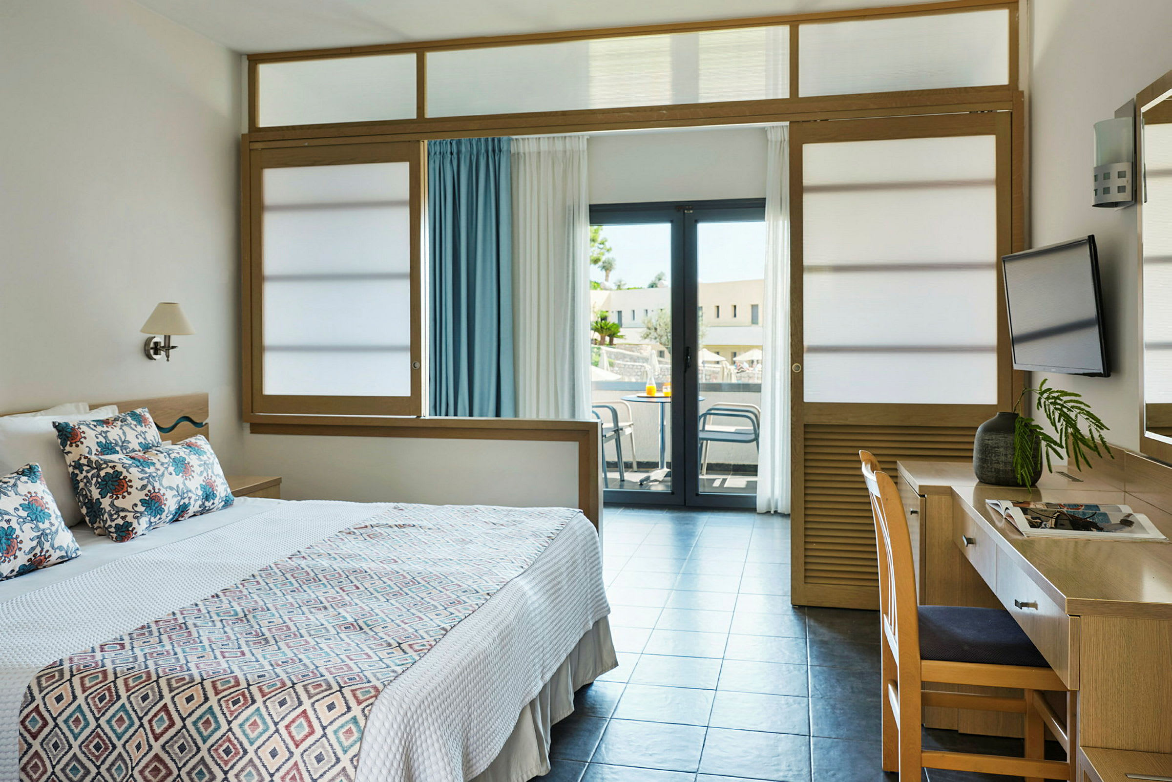 Hotellrum med en säng, skrivbord och balkong. (AI-genererad text)