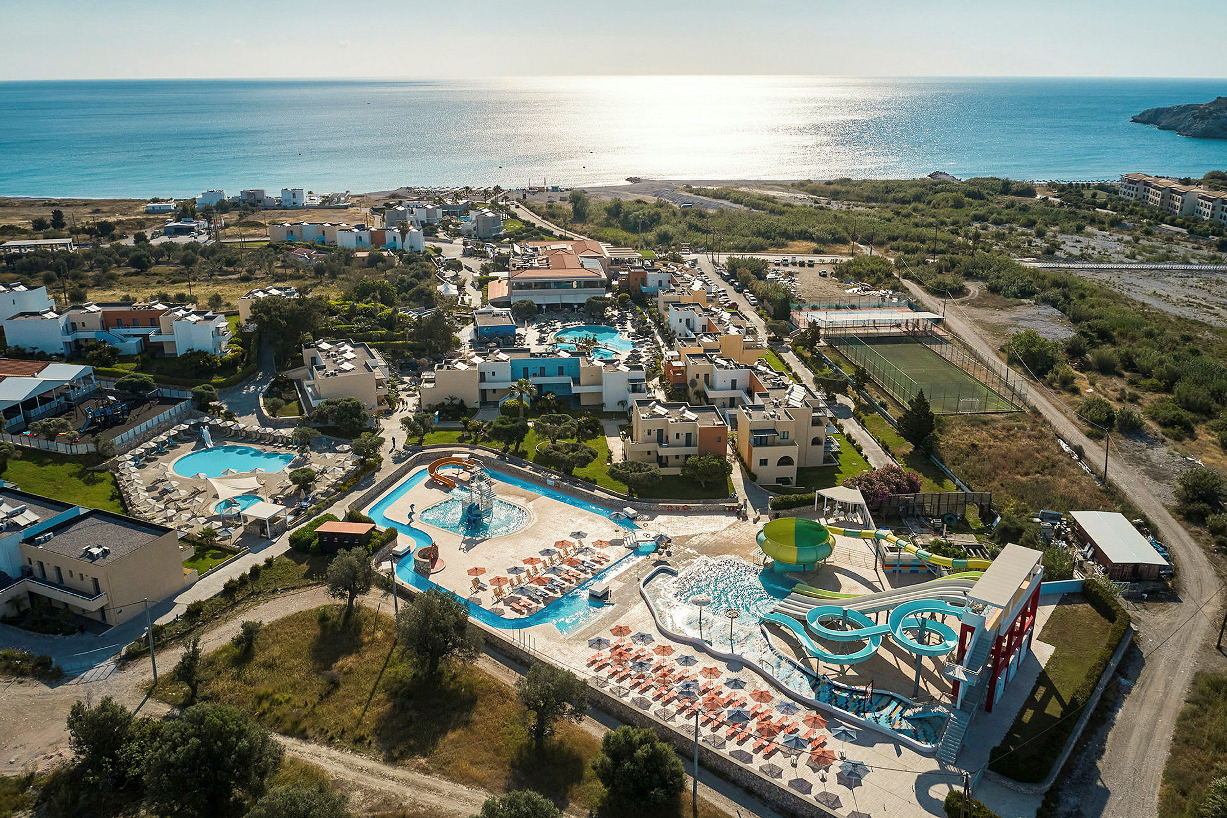 Flygbild av en resort vid havet med poolområden och vattenrutschkanor. (AI-genererad text)