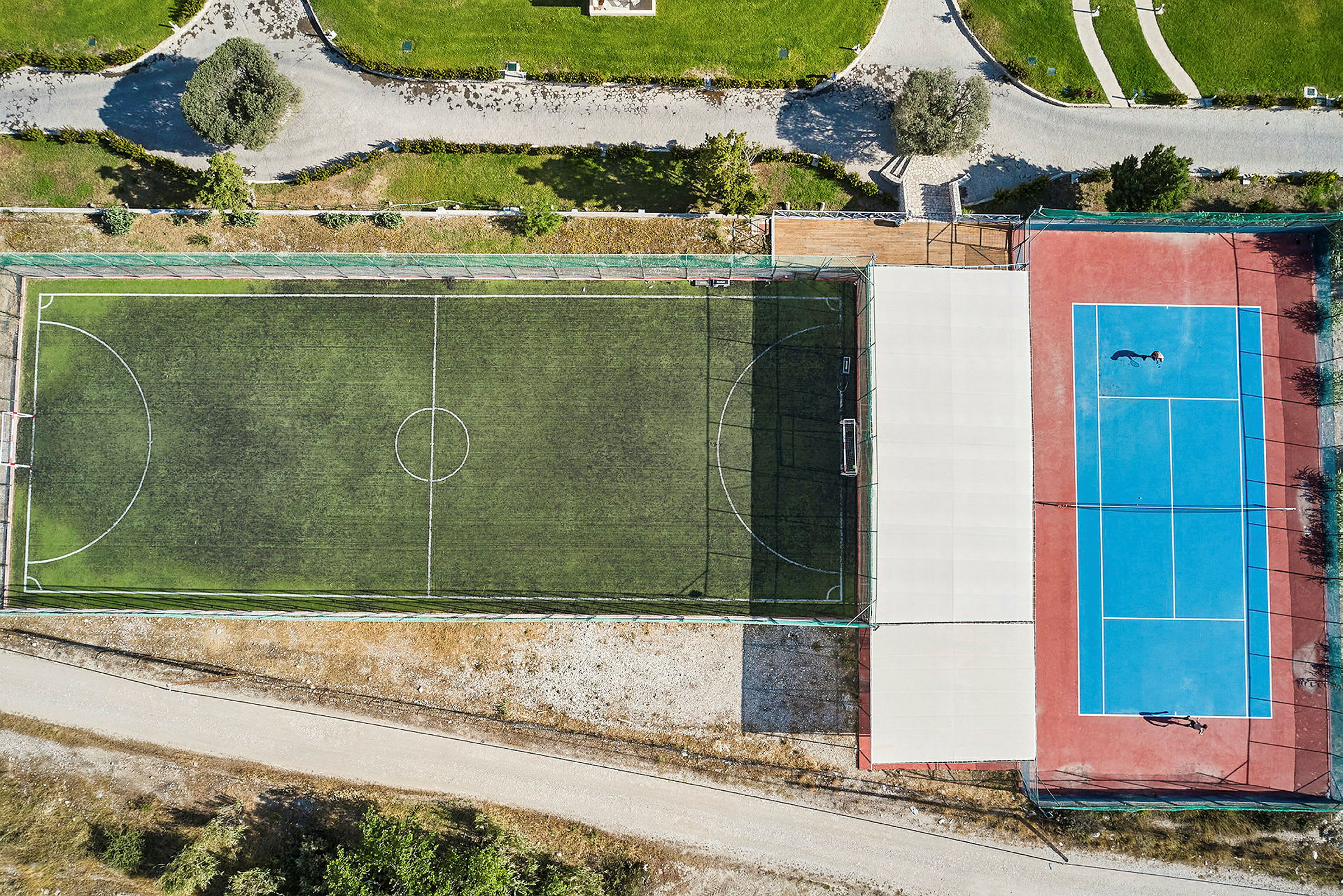 Flygbild av en fotbollsplan och en tennisplan bredvid varandra. (AI-genererad text)