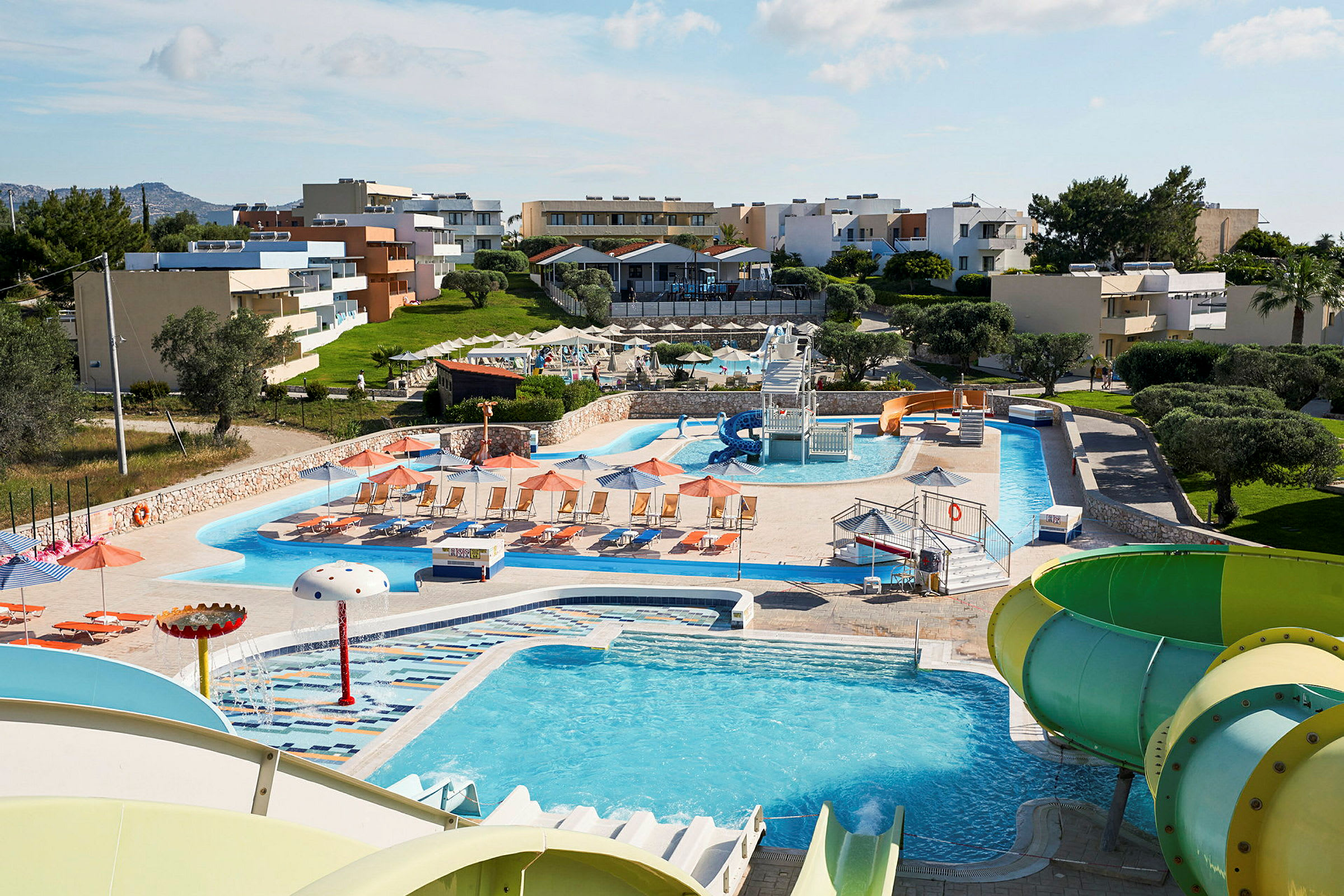 Ett semesterkomplex med flera byggnader, poolområden och vattenrutschbanor. (AI-genererad text)