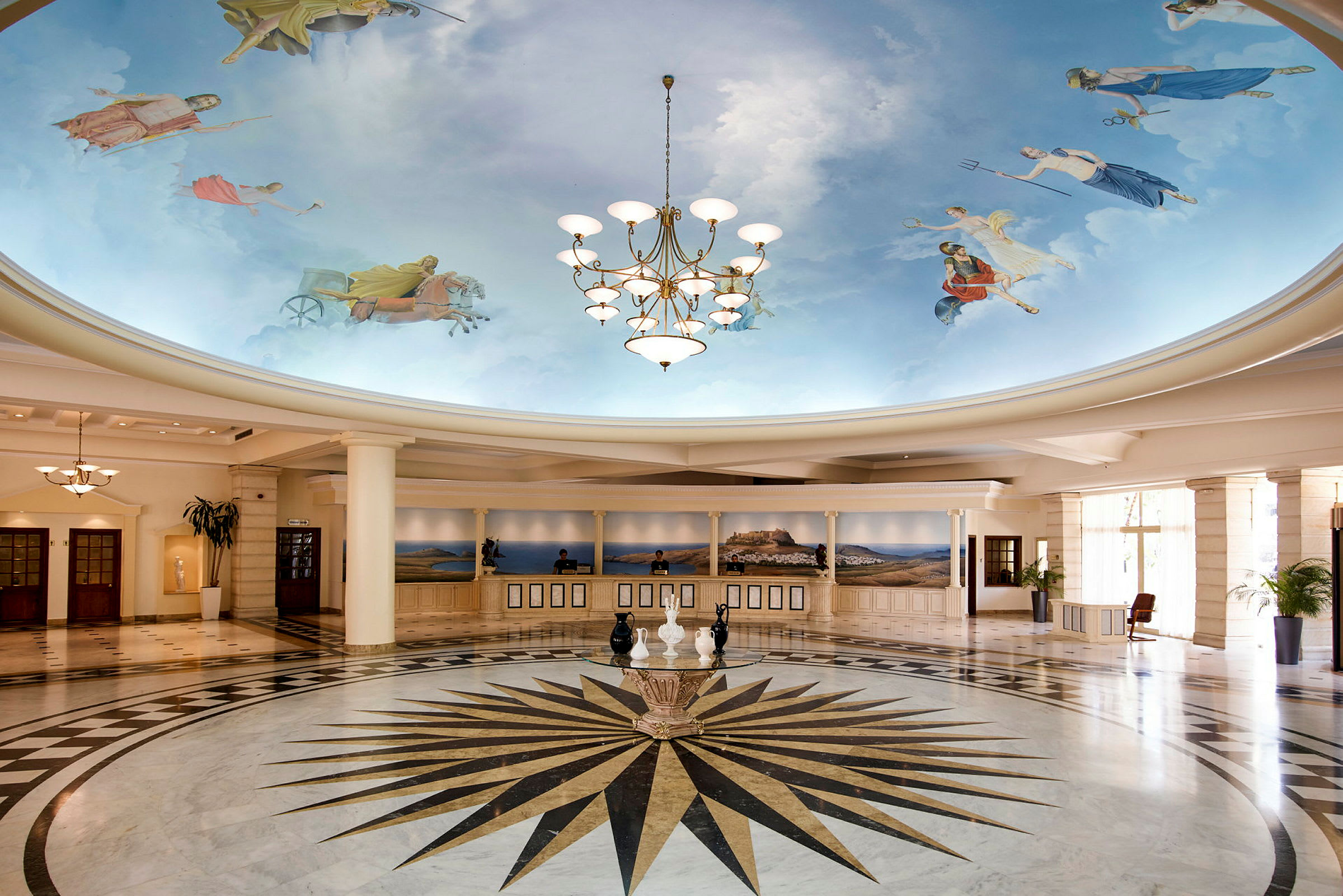 Ett hotellobby med målade himmelmotiv på taket och en ljuskrona. Det finns en reception längre bak. (AI-genererad text)